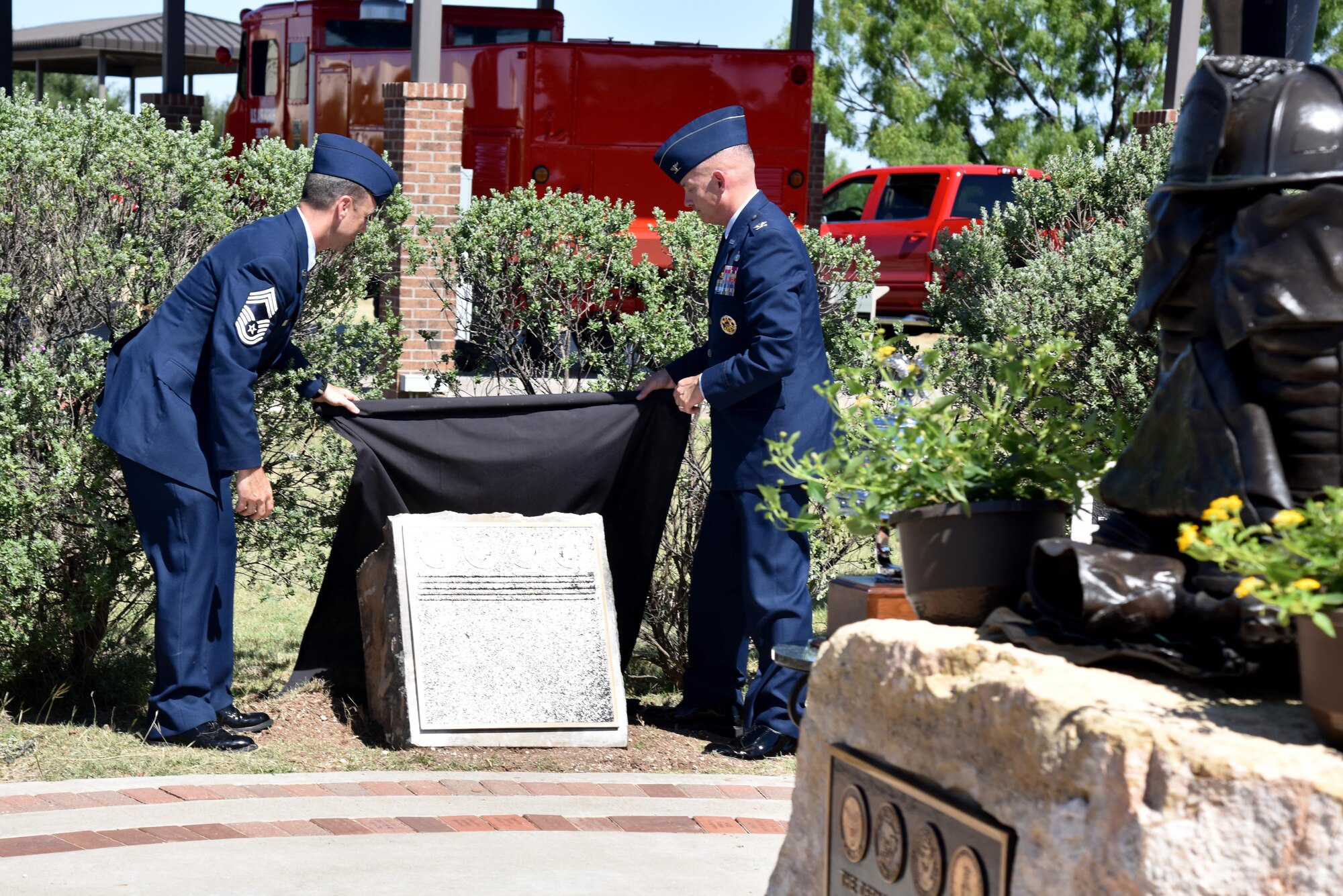U.S. Air Force Chief Master Sgt. Scott Knupp, Air Force fire chief, and Col. Michael Downs, 17th Training Wing commander, unveil the plaque with the names of the five fallen firefighters honored at a memorial service at the Department of Defense Fallen Firefighter Memorial on Goodfellow Air Force Base, Texas, May 12, 2017. The plaque includes the two firefighters that died in the past two years and the three that died in Vietnam.  (U.S. Air Force photo by Staff Sgt. Joshua Edwards/Released)