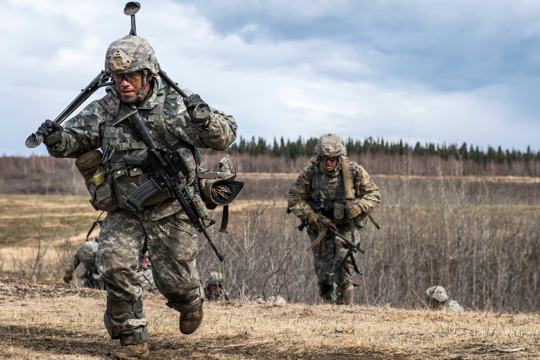A soldier carrying a machine gun tripod moves out to take a defensive position overlooking an objective during live-fire assault training as part of joint exercise Northern Edge at Fort Greely, Alaska, May 10, 2017. Army photo by Staff Sgt. Daniel Love