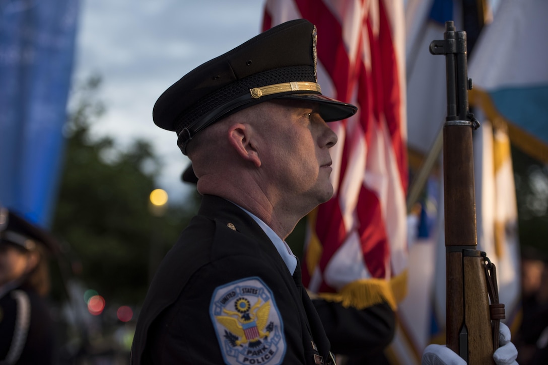 A member of the United States Park Police Honor Guard presents arms during the opening ceremony of the 29th Annual Candlelight Vigil honoring fallen police officers from around the country on the National Mall in Washington, D.C., May 13, 2017. Approximately 300 police officers' names were read, engraved into the National Police Memorial. Among those names was Staff Sgt. James D. McNaughton, a U.S. Army Reserve military police who was the first New York City police officer killed in action while deployed to Iraq, Aug. 2, 2005. (U.S. Army Reserve photo by Sgt. Audrey Hayes)