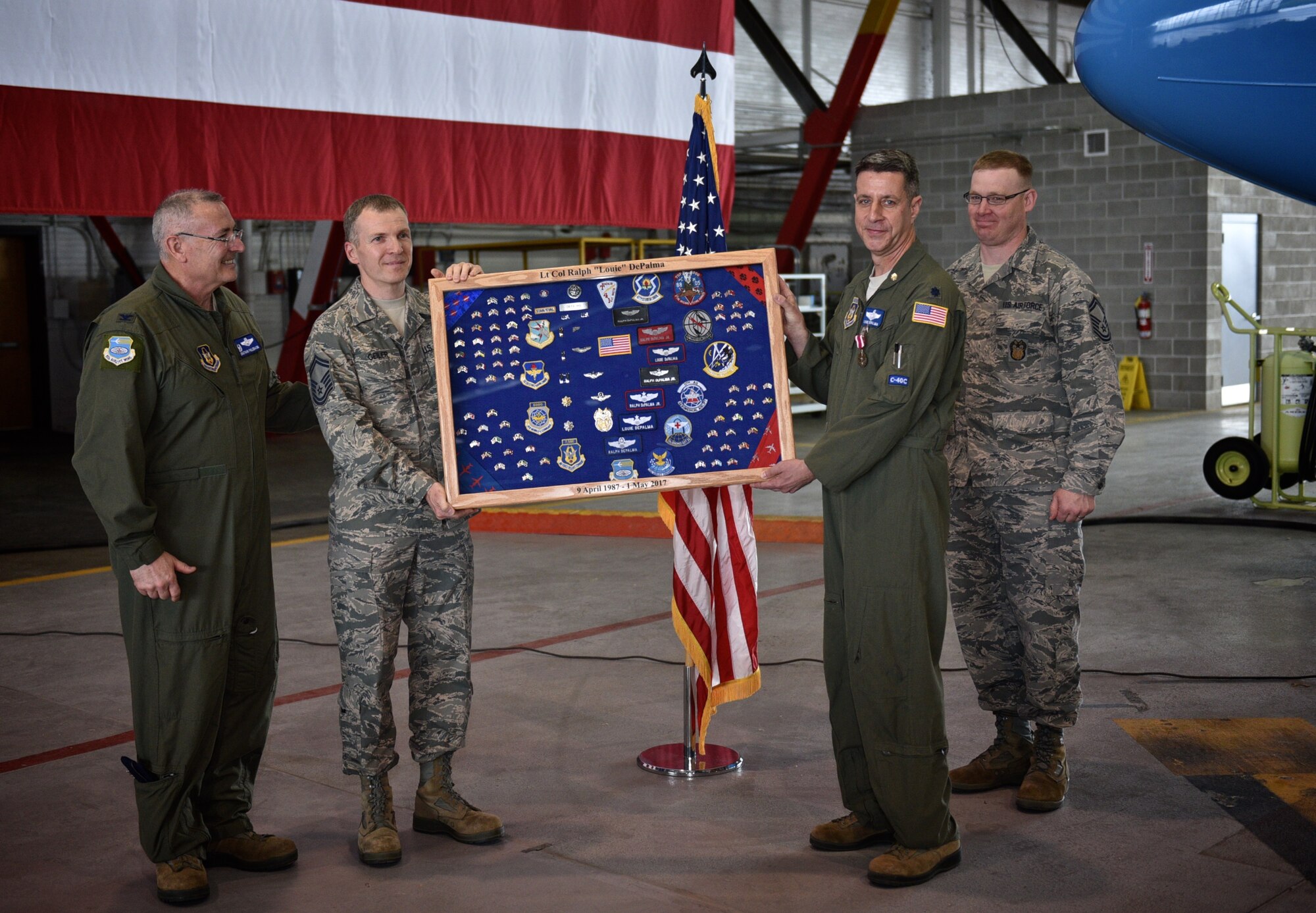 Left to right, Col Jonathan Philebaum, commander, 932nd Airlift Wing looks on as Senior Master Sgt. Curtis Geiler presents Lt. Col. Ralph "Louie" DePalma with a retirement shadow box with help from fellow Inspector General office member Senior Master Sgt. Wayne Cantwell, May 6, 2017, Hangar 1, Scott Air Force Base, Illinois. The shadow box is a reflection of a service member's military career and commonly presented as a gift upon retirement. (U.S. Air Force photo by Tech. Sgt. Christopher Parr)