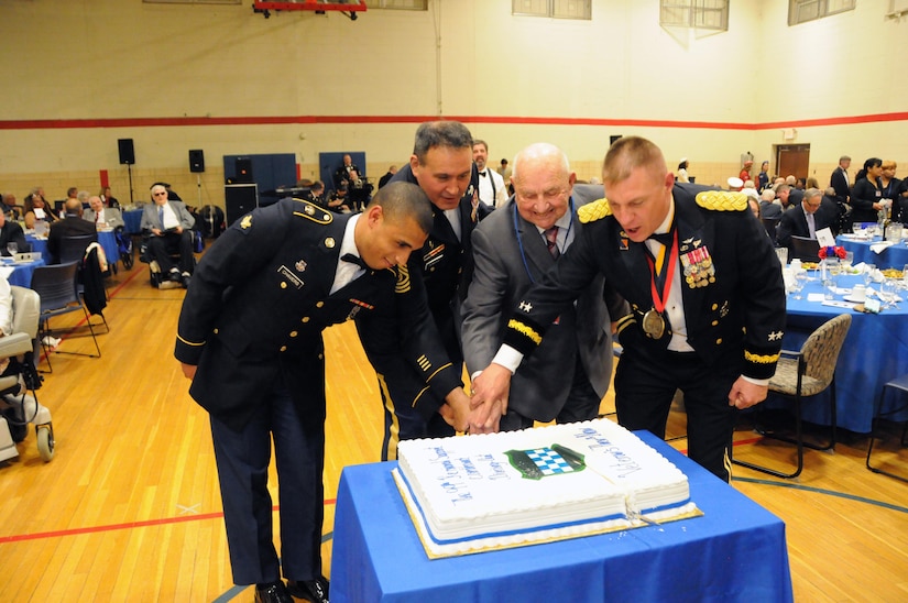 Spc. Aaron Chavers (left) and John Ruszkai (second from right), a World War II veteran, help cut the cake May 12 during the U.S. Army Reserve’s 99th Regional Support Command dining out on Joint Base McGuire-Dix-Lakehurst, New Jersey.  The theme of the event was “Veterans: Then and Now.”  More than 100 veterans from area veteran homes were invited to attend.  Command Sgt. Maj. Almeida, command sergeant major for the 99th RSC, and Maj. Gen. Troy D. Kok, commanding general for the 99th RSC, are also pictured.