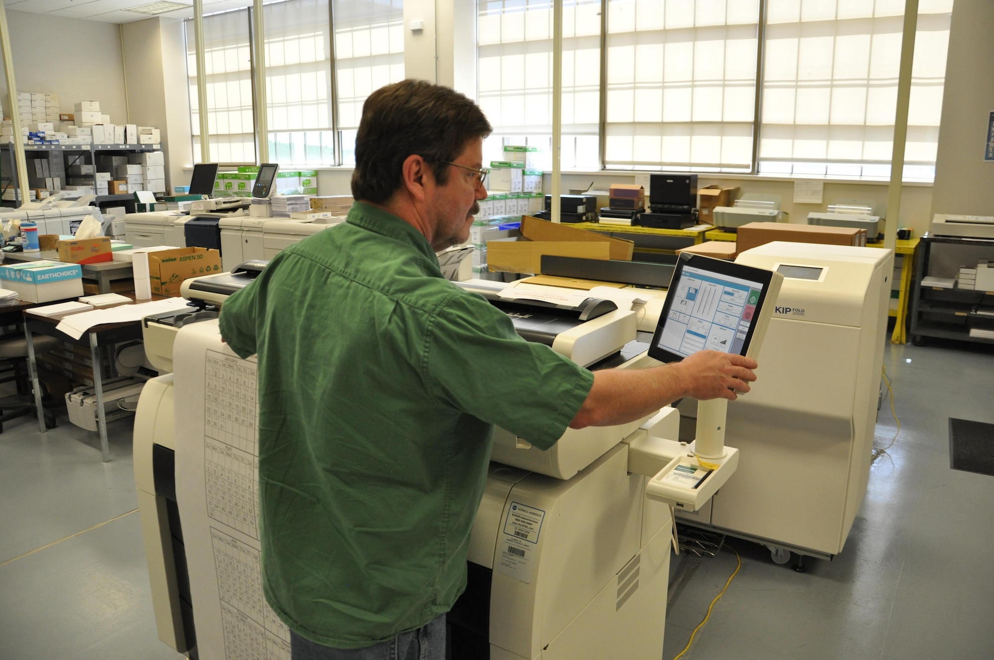 Tim Pillion, document automation specialist runs a large document through the 36” Kip 7770 Large Format Scanner. (U.S. Air Force photo / W. Eugene Barnett)