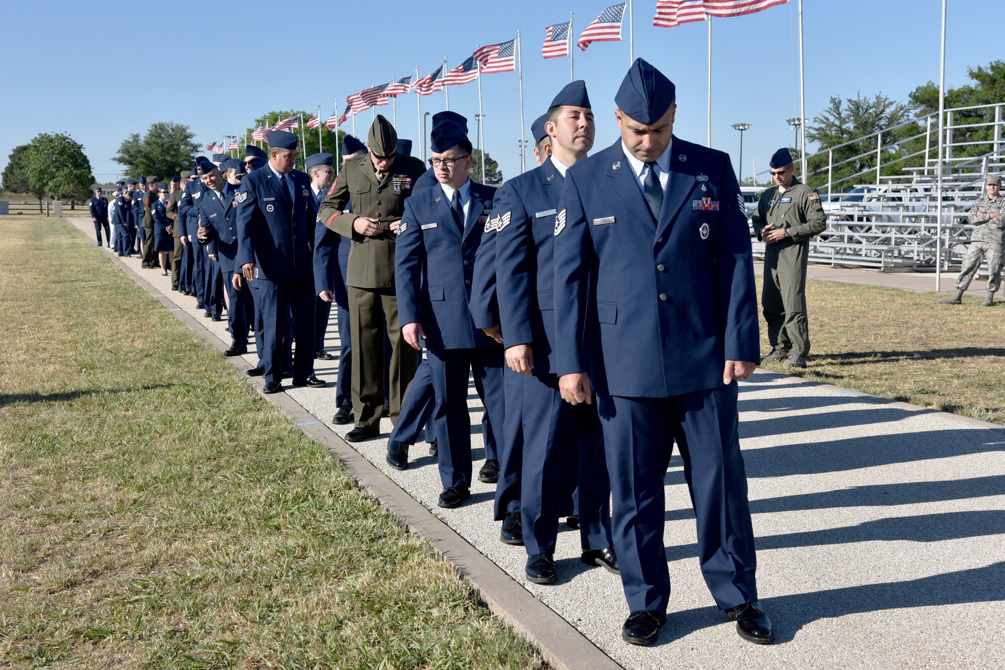 Service members earning their Community College of the Air Force degree wait in line before the CCAF graduation at the parade field on Goodfellow Air Force Base, Texas, May 12, 2017. Fifty-six Airmen, four Marines and a Sailor graduated the program that is the Air Force equivalent to getting an associate degree. (U.S. Air Force photo by Staff Sgt. Joshua Edwards/Released)
