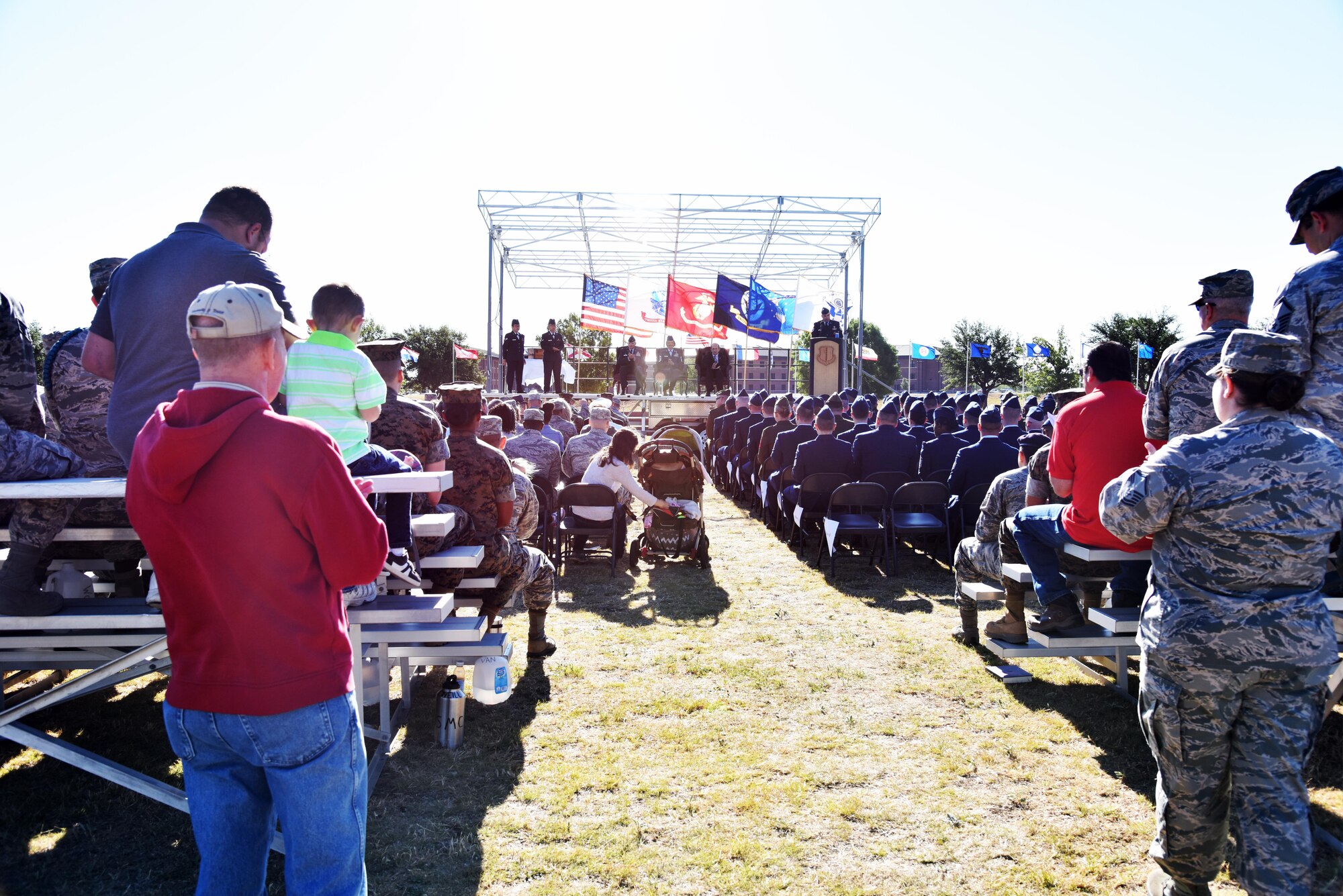 Guests and graduates watch the Community College of the Air Force graduation at the parade field on Goodfellow Air Force Base, Texas, May 12, 2017. The Top 3 hosted the event to recognize individuals who completed the Air Force’s equivalent to a two-year degree program. (U.S. Air Force photo by Staff Sgt. Joshua Edwards/Released)