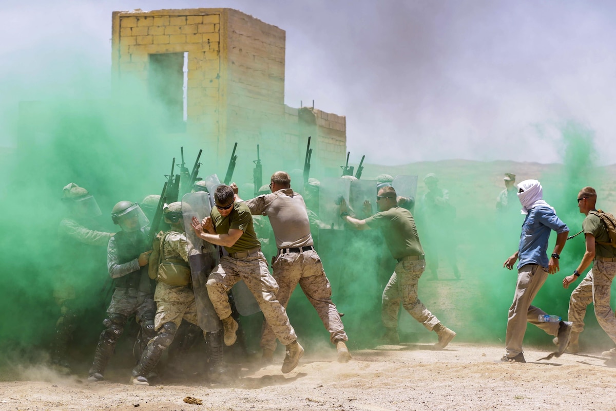 Marines and Jordanian troops participate in training under green smoke.