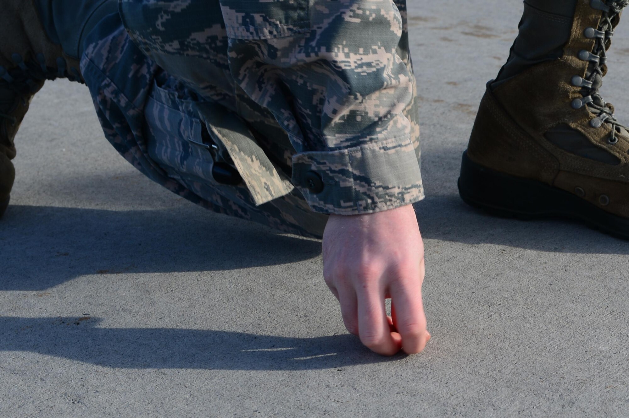 A U.S. Air Force Airman from the 354th Fighter Wing, picks up foreign object debris (FOD) during a wing-wide FOD walk, May 15, 2017, at Eielson Air Force Base, Alaska. FOD walks are held to remove debris from the flightline, which can potentially cause harm to an aircraft. (U.S. Air Force photo by Airman Eric M. Fisher)