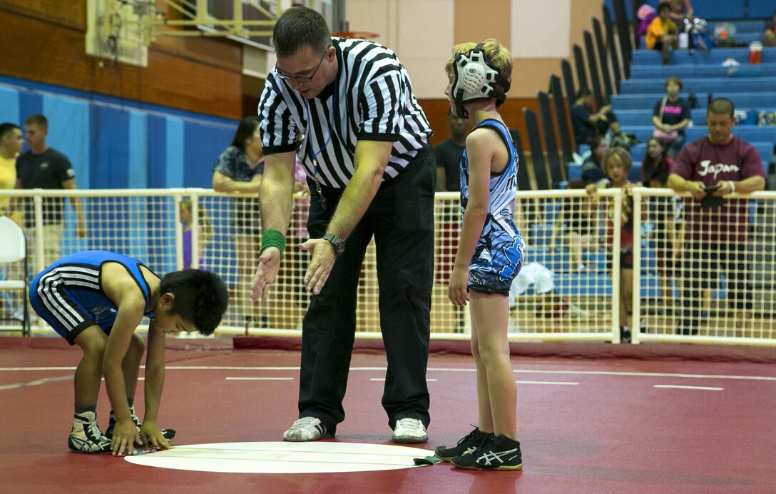 Navy Lt. David Keim referees youth wrestlers during the Okinawa Open Championship May 13 on Marine Corps Air Station Futenma, Okinawa, Japan. Approximately 100 wrestlers from the Okinawa Youth Wrestler League competed alongside 70 wrestlers from the Gladiator Wrestling League. The Okinawa Open Championship is the largest youth wrestling tournament in Okinawa. Keim is a chaplain who volunteers as a referee with the Gladiator Wrestling League. (U.S Marine photo by Lance Corporal Tayler P. Schwamb) 