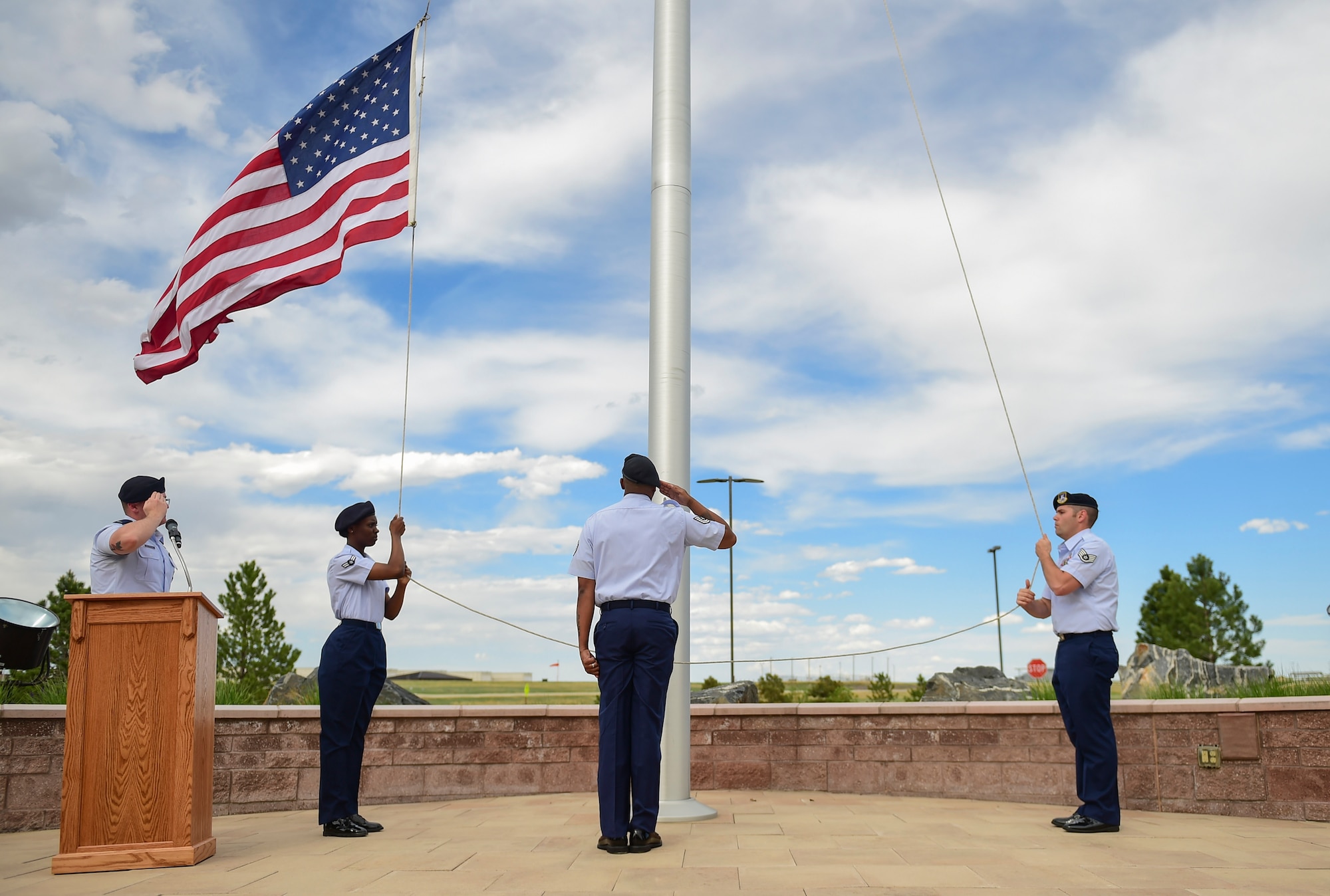 460th Security Forces Squadron Airmen render salutes as the American flag is lowered during a Retreat ceremony May 15, 2017, on Buckley Air Force Base, Colo. The Retreat ceremony recognizes fallen civilian and military law enforcement officers with the 21-gun salute, the playing of TAPS and the National Anthem. (U.S. Air Force photo by Airman Jacob Deatherage/Released)