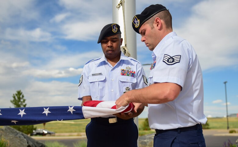 Tech Sgt. Michael Thomas, 460th Security Forces Squadron physical security NCO in-charge, and Staff Sgt. Daniel Leutwyler, 460th SFS resource protection NCO in-charge, fold the American flag May 15, 2017, during the Retreat ceremony on Buckley Air Force Base, Colo. The Retreat ceremony recognizes fallen civilian and military law enforcement officers with the 21-gun salute, the playing of TAPS and the National Anthem. (U.S. Air Force photo by Airman Jacob Deatherage/Released)