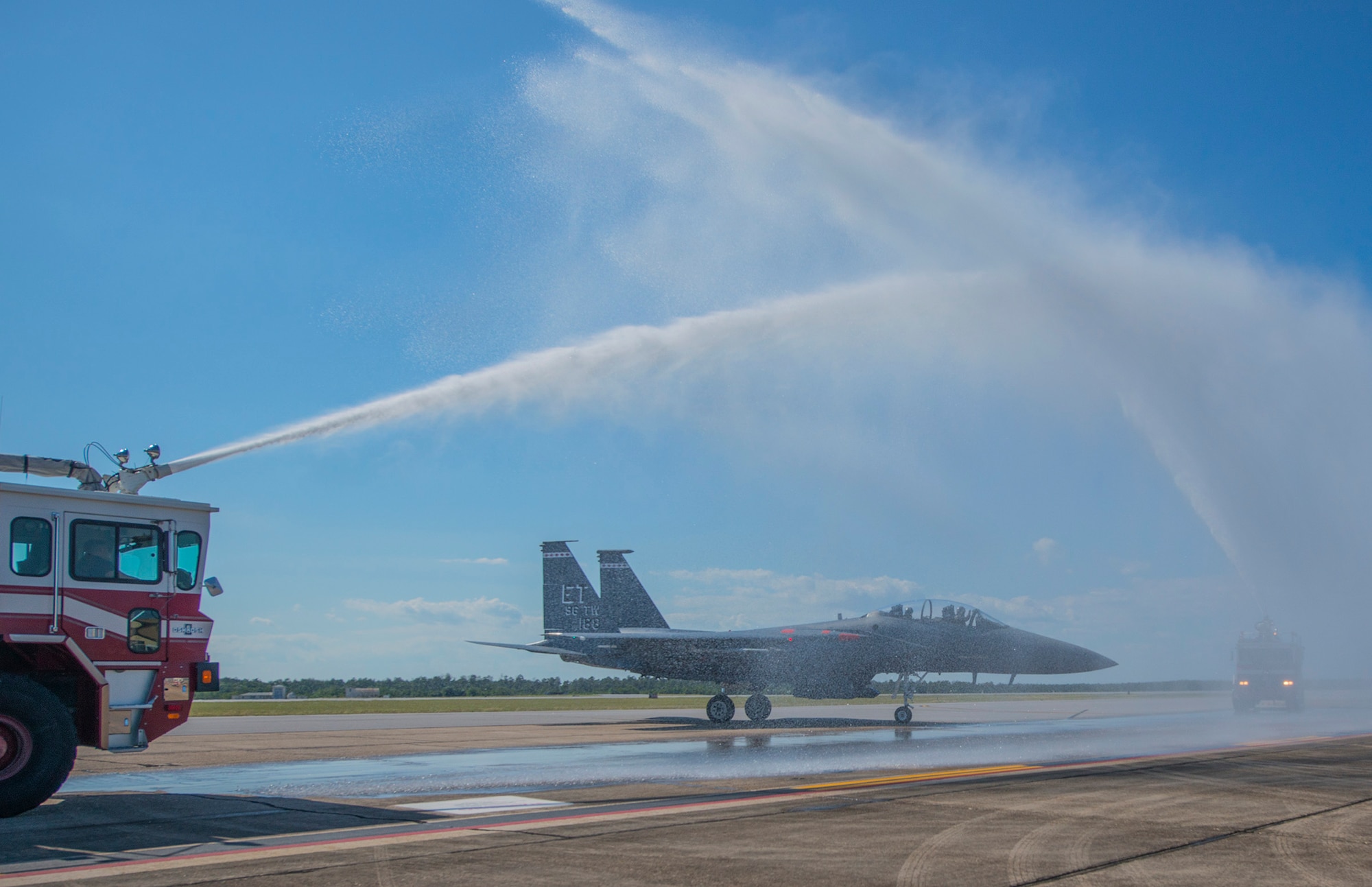 Fire engines from the 96th Civil Engineer Group flank Brig. Gen. Christopher Azzano’s F-15 Eagle while they hose down the aircraft during his fini flight at Eglin Air Force Base, Fla. May 15. The fini flight is a symbol of a member’s final flight with the unit or base. Azzano’s new assignment will take him to Wright-Patterson Air Force Base in Ohio to take command of the Directorate of Air, Space and Cyberspace Operations. (U.S. Air Force photo/Ilka Cole) 
