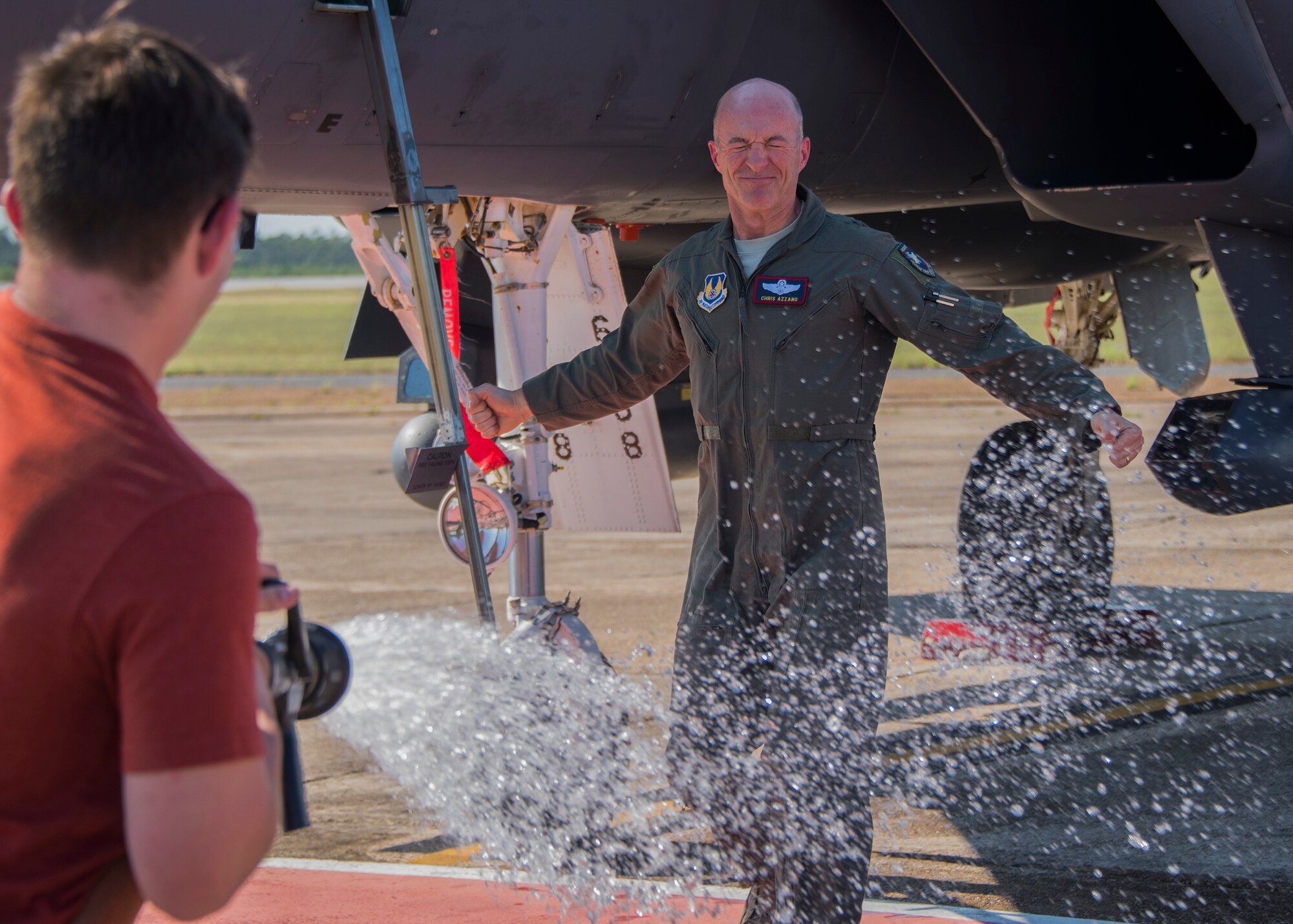 Brig. Gen. Christopher Azzano, 96th Test Wing commander, braces for a soaking while his son, Steven, hoses him down during his fini flight at Eglin Air Force Base, Fla. May 15. The fini flight is a symbol of a member’s final flight with the unit or base. Azzano’s new assignment will take him to Wright-Patterson Air Force Base in Ohio to take command of the Directorate of Air, Space and Cyberspace Operations. (U.S. Air Force photo/Ilka Cole)