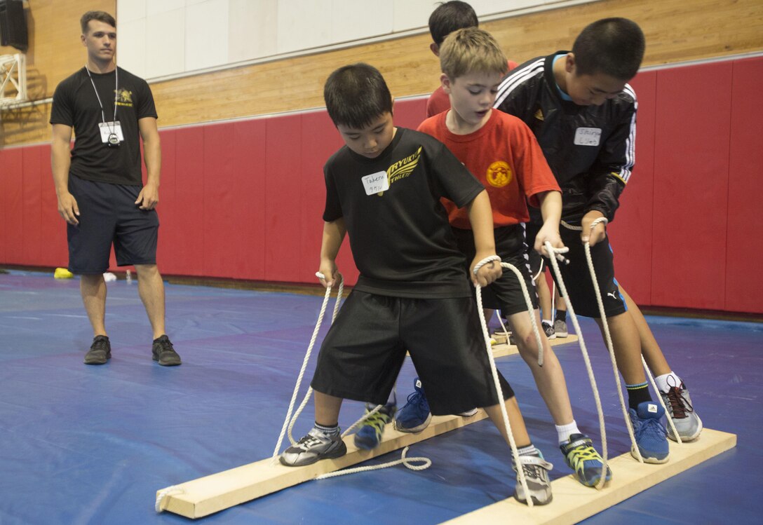 Local Okinawan children and children of the Young Marines program participate in a team effort exercise while attending the Young Marine Battalion Field Meet on Camp Hansen, Okinawa, Japan, May 13, 2017. The meet included team building exercises which allowed interaction between local Okinawan children and American children who are in the YMP. (U.S. Marine Corps Photo by Lance Cpl. Deseree Kamm)
