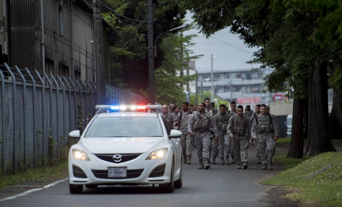 Participants in the Memorial 5K Ruck March are escorted by a 374th Security Forces Squadron squad car, May 15, 2017, at Yokota Air Base, Japan. The Memorial 5K Ruck March had approximately 75 participants from the 374 SFS, Office of Special Investigations and various members of base leadership. (U.S. Air Force photo by Airman 1st Class Donald Hudson)