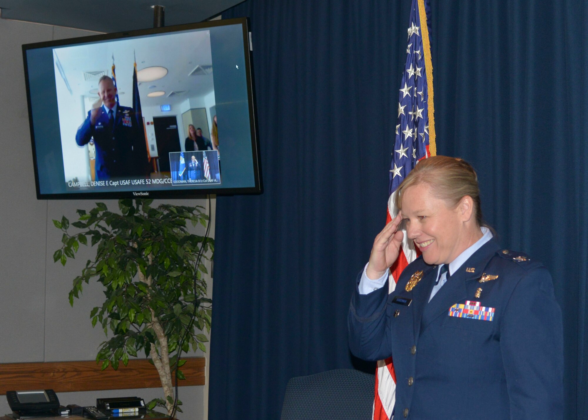 Col. Theresa Goodman, Air Force Inspectiion Agency medical inspector, salutes her brother, Col. Joseph McFall, 52nd Fighter Wing commander, during her promotion ceremony via video teleconferencing technology, May 15, 2017. Goodman is stationed at Kirtland Air Force Base, New Mexico, 5296 miles away from Spangdahlem.