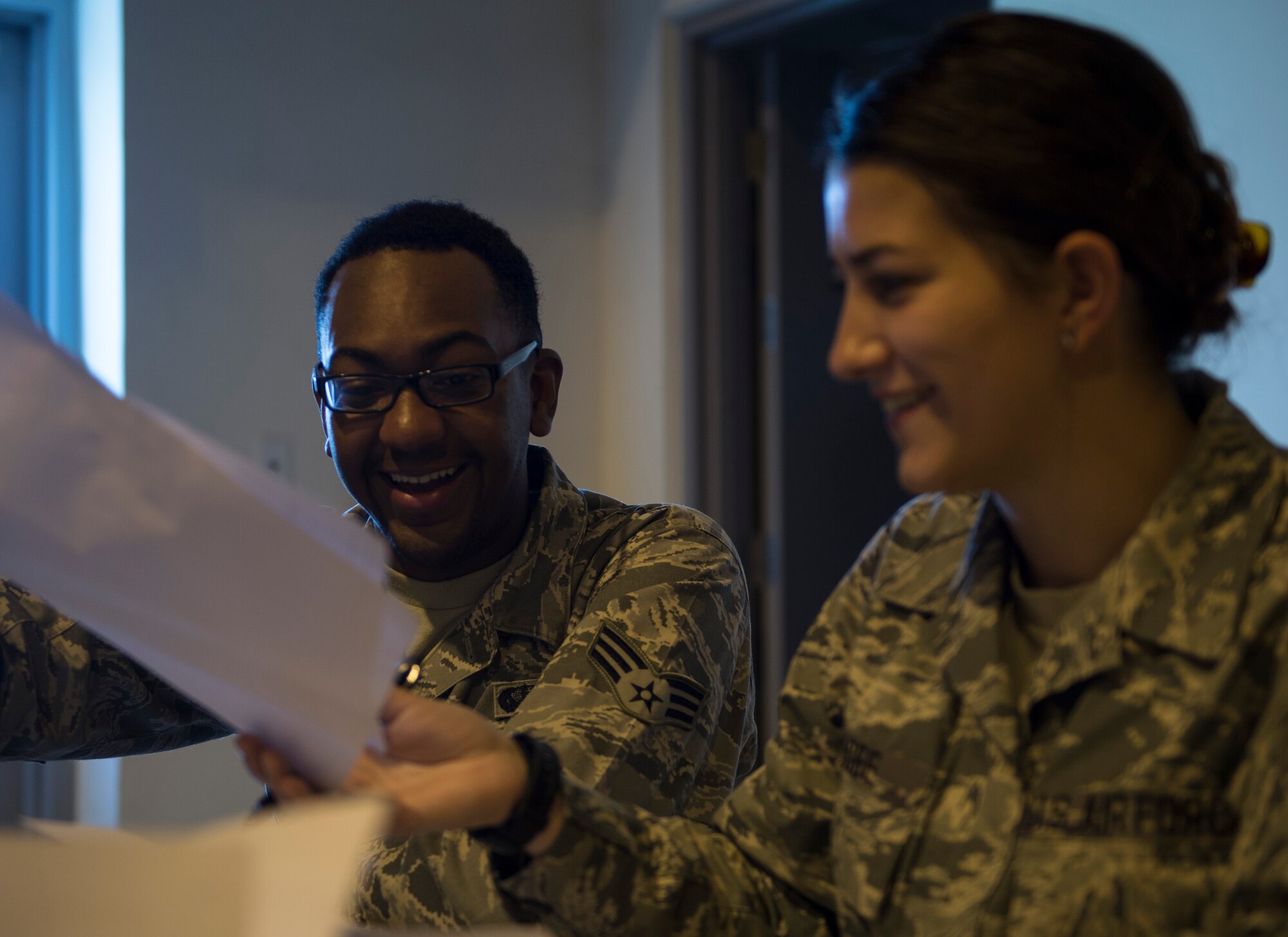 U.S. Air Force Senior Airman Jabari Superville, left, hands two shipping manifests to Senior Airman Airiana Magee, both with the 379th Expeditionary Force Support Squadron to ensures the invoice matches the shipment at Al Udeid Air Base, Qatar May 10, 2017. Each week, a small team of Airmen work together to review shipments of produce, making sure the numbers matches the quantity received and that the quality of the produce meets standards. (U.S. Air Force photo by Tech. Sgt. Amy M. Lovgren)
