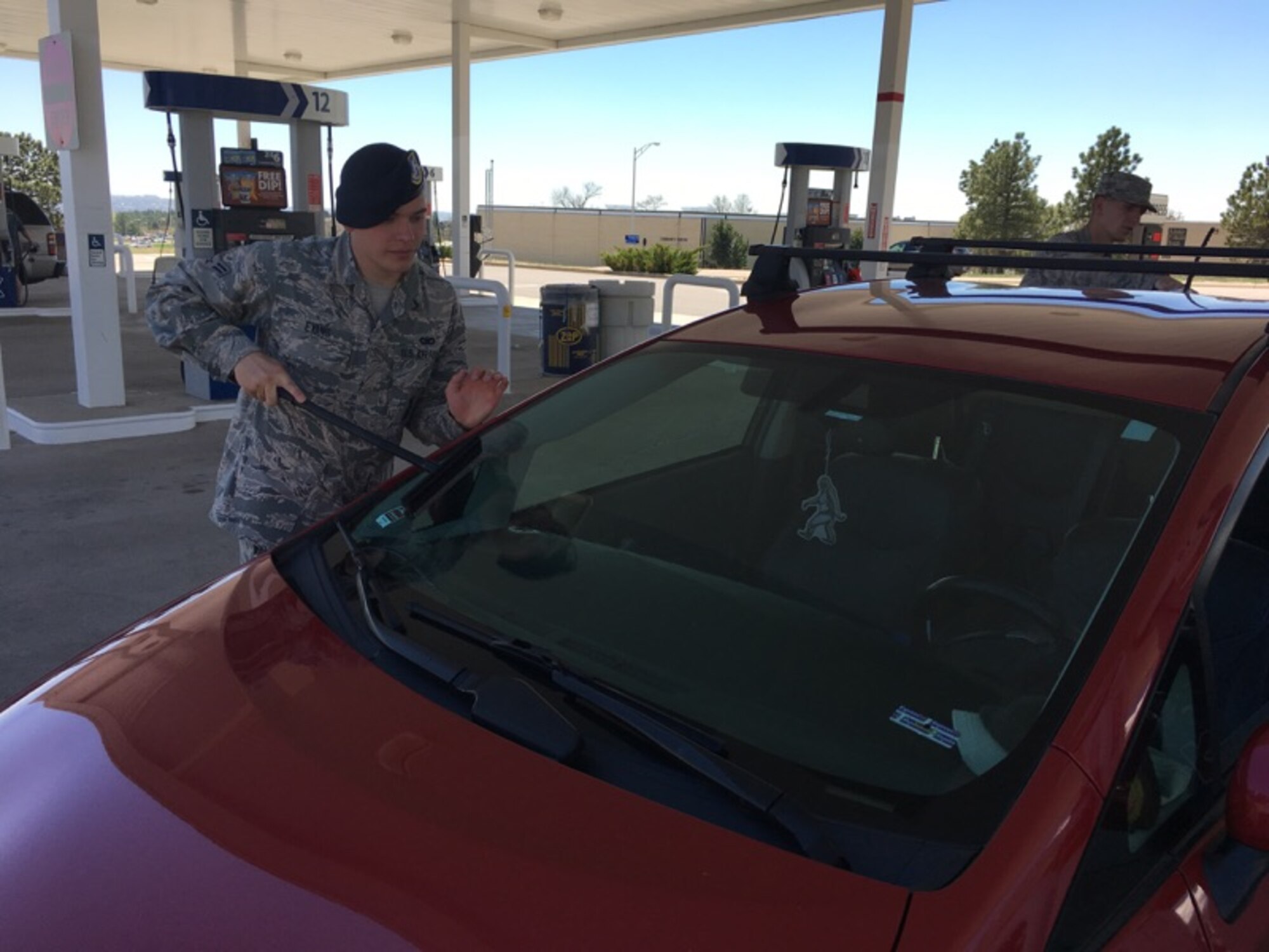 An 10th Security Forces Squadron Defender cleans the windshield of a car at the U.S. Air Force Academy Shopette, May 12, 2017. He and 16 other Defenders raised more than $3,000 for the Air Force Assistance Fund by soliciting donations at the shopette and cleaning customers' windshields. for the AFAF. (Courtesy photo/Chief Master Sgt. Shadd McKee)