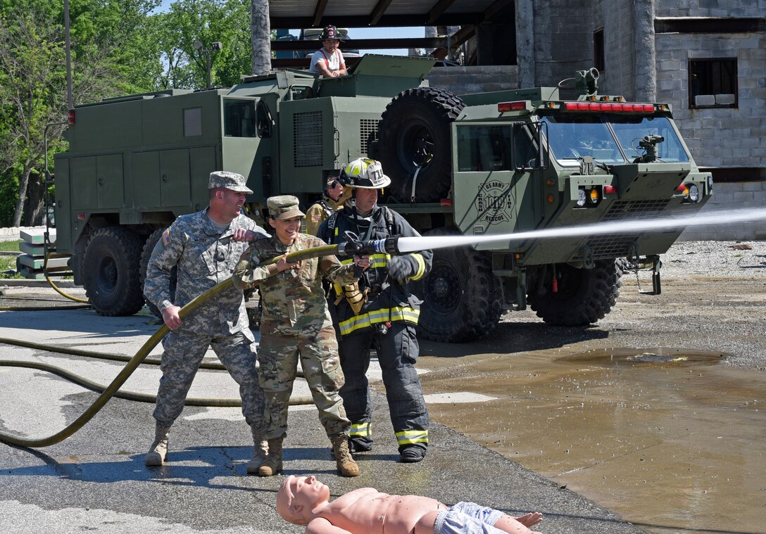 A Soldier with the Indiana National Guard’s 719th Engineer Firefighter Detachment Headquarters shows Pvt. Justine Gutierrez with the 205th Press Camp Headquarters and Sgt. Clinton Massey with the 206th Broadcast Operations Detachment how to operate a fire hose effectively during firefighter training at Muscatatuck Urban Training Center, May 13. (U.S. Army Reserve photo by Sgt. Xavier Reyes, the 201st Press Camp Headquarters from Bell Ca.)