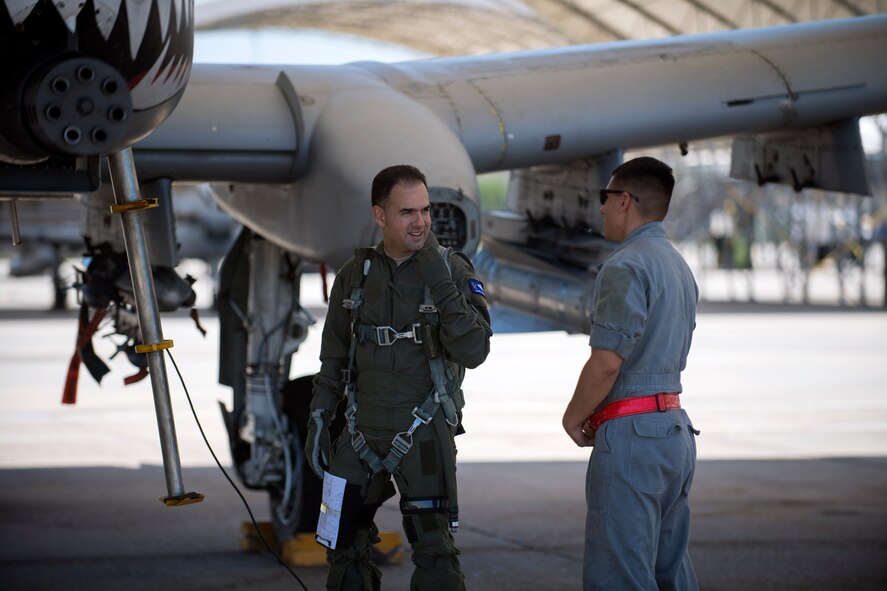 Col. Mark Barrera, 23d Wing vice commander, talks to Airman 1st Class Jesse Acevedo, 75th Fighter Squadron crew chief, before his fini flight from Moody Air Force Base, Ga., May 15, 2017. Upon completion of their final flights, military aviators are hosed down with water by their comrades, family, and friends before they depart their squadron. Barrera will continue his Air Force career by attending the Joint Military Attaché School to become an Air Attaché in Italy. During this tenure, he will act as an embassy liaison with host-nation defense establishments, openly observe and report developments and significant events, and actively participate in national security and operational policy development and coordination. (U.S. Air Force photo by Airman 1st Class Daniel Snider) 