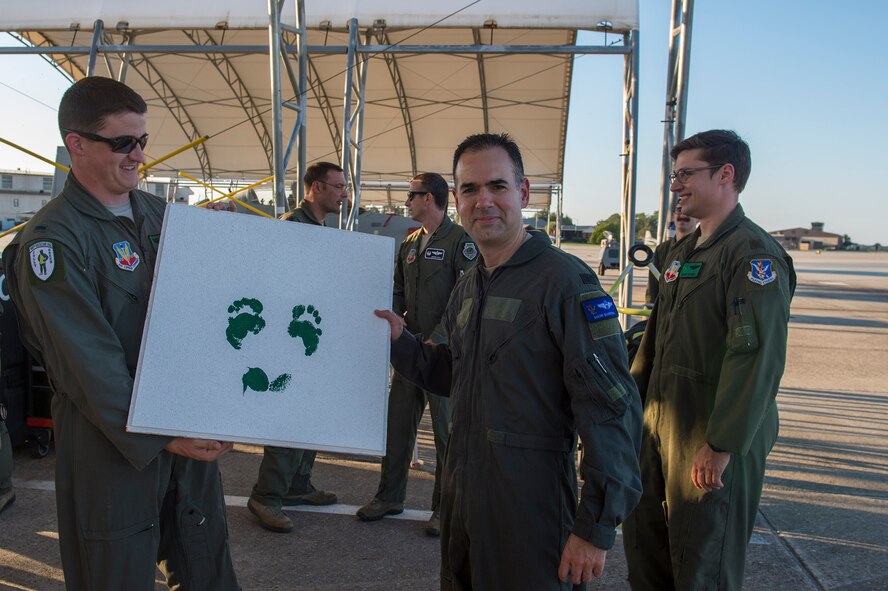 Col. Mark Barrera, 23d Wing vice commander, poses with a tile of his feet imprint after completing his fini flight from Moody Air Force Base, Ga., May 15, 2017. Upon completion of their final flights, military aviators are hosed down with water by their comrades, family, and friends before they depart their squadron. Barrera will continue his Air Force career by attending the Joint Military Attaché School to become an Air Attaché in Italy. During this tenure, he will act as an embassy liaison with host-nation defense establishments, openly observe and report developments and significant events, and actively participate in national security and operational policy development and coordination. (U.S. Air Force photo by Senior Airman Greg Nash)