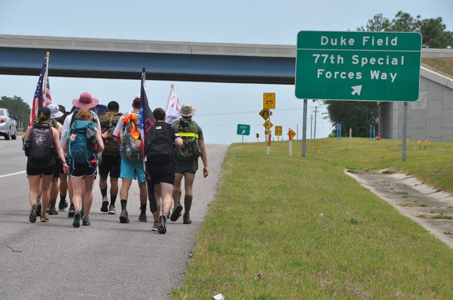 Marines, Sailors and Midshipmen from Auburn University make their way past the entrance to Duke Field, Fla. May 9 during their recent 201-mile journey from their campus headquarters to the Black Hawk memorial in Navarre, Fla.  The ruck marchers made the trip to honor the memory of Raider 7, an elite group of Marine Raiders who perished in a helicopter training accident in Navarre March 10, 2015.  (U.S. Air Force photo/Dan Neely)