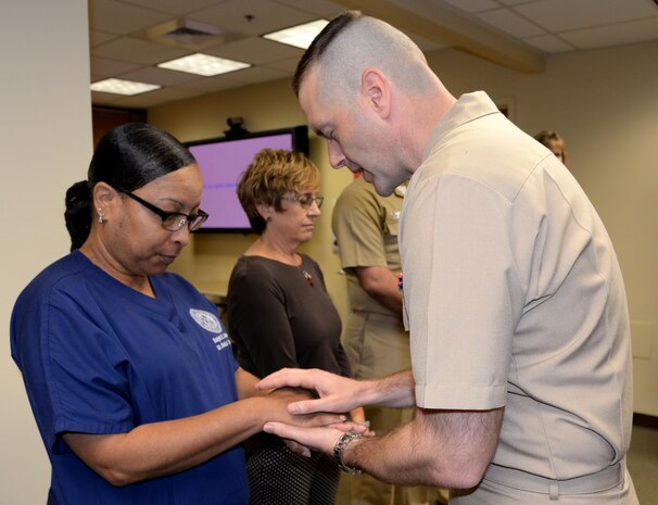 Lt. Grant Mayfield, right, chaplain, Naval Support Activity, blesses the hands of Stacey Belton, nurse, Veterans Affairs Goose Creek Outpatient Clinic, during a "Blessing of the Hands" ceremony May 8 at Naval Health Clinic Charleston located on Joint Base Charleston - Weapons Station, in celebration of Nurses Week May 6-12. The "Blessing of the Hands" ceremony, a hospital tradition practiced around the world during Nurses Week, honors nurses who use their hands in many ways to bring healing to patients.