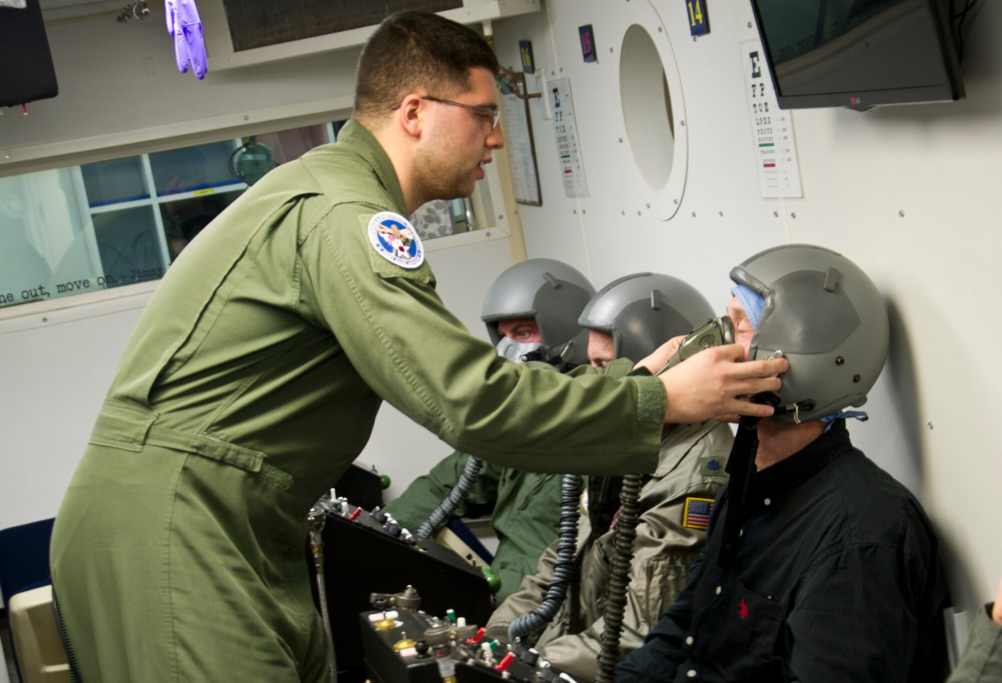 Senior Airman Christopher Connolly, 779th Aerospace Medical Squadron physiologist, assists David Kinsella with sealing his oxygen mask inside an altitude simulator chamber March 16, 2017, at Joint Base Andrews, Md. As an inside observer, Connolly was nearby to assist if Kinsella or the other students had physiological complications while experiencing varying levels of air pressure. (U.S. Air Force photo by Staff Sgt. Joe Yanik)