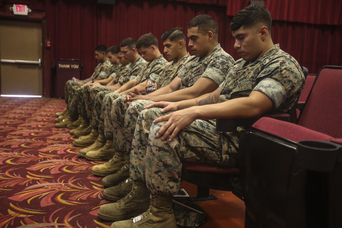 Marines bow their heads for prayer during the Solar Ready Vets graduation ceremony at the theater aboard Marine Corps Base Hawaii on May 11, 2017. The six-week course provided the Marines with basic knowledge of photovoltaic systems and prepared them for the North American Board of Certified Energy Practitioners PV Associates exam. Upon completion of the exam, the Marines will be qualified for solar energy related occupations. (U.S. Marine Corps photo by Lance Cpl. Matthew Kirk)