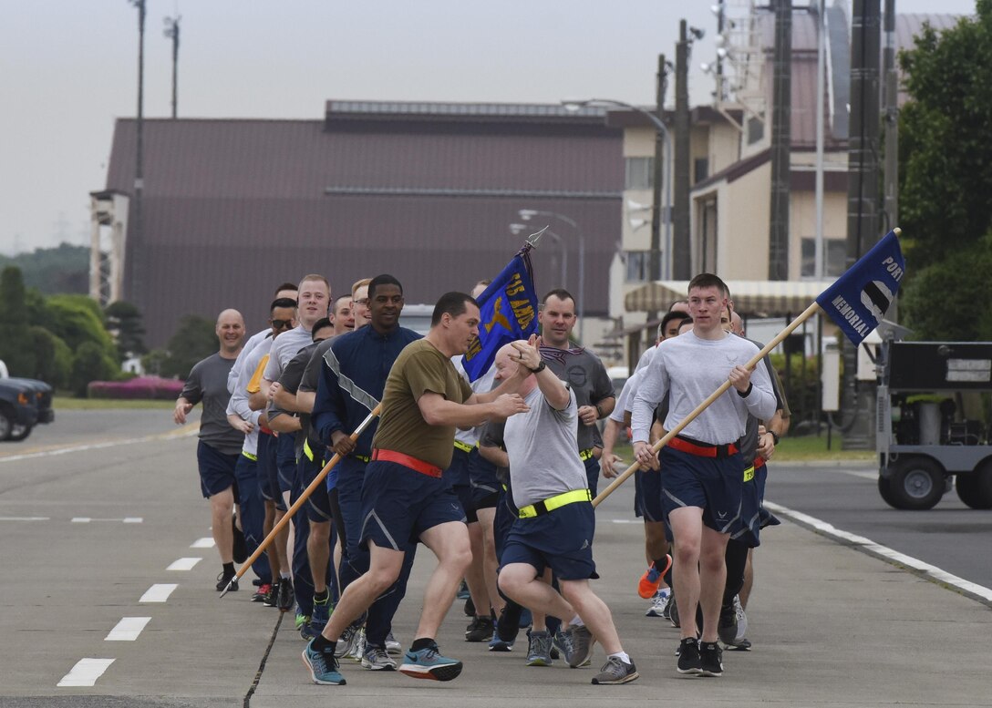 Airmen 1st Class Kristopher Wrentmore, 374th Logistics Readiness Squadron aerial delivery rigger, left, and Capt. Michael McDonald, 374th Airlift Wing chaplain, high-five each other while running during the Port Dawg Memorial Run at Yokota Air Base, Japan, May 15, 2017. The 730th Air Mobility Squadron hosted the Port Dawg Memorial Run in honor of fallen air transportation specialists and brought awareness to Airmen whose job involves many risk factors while also trying to prevent future mishaps. (U.S. Air Force photo by Machiko Arita)
