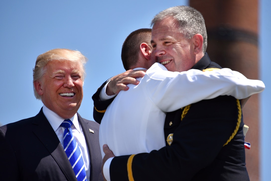 President Donald Trump looks on and smiles as a father congratulates his son during the 136th Coast Guard Academy commencement in New London, Conn., May 17, 2017. Coast Guard photo by Petty Officer 2nd Class Patrick Kelley