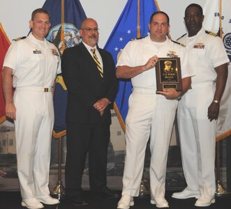 DAHLGREN, Va. (May 17, 2017) - Lt. Cmdr. Wesley Simon holds the C.J. Rorie Award moments after receiving it from Naval Surface Warfare Center Dahlgren Division (NSWCDD) leadership at the command's annual honor awards ceremony. Simon was recognized for his contributions as NSWCDD's senior watch officer and as Aegis Ballistic Missile Defense (BMD) lead combat system engineer. "His support of NSWCDD military operations has added to the depth of military expertise available at Dahlgren and his vision, leadership, technical acumen, and determination within Aegis BMD have provided the warfighter with new technology, extended service life, and combat viability for fielded Aegis combatants," according to the citation. Standing left to right: Combat Direction Systems Activity Commanding Officer Cmdr. Andrew Hoffman; NSWCDD Technical Director John Fiore; Simon; and NSWCDD Commanding Officer Capt. Godfrey 'Gus' Weekes.