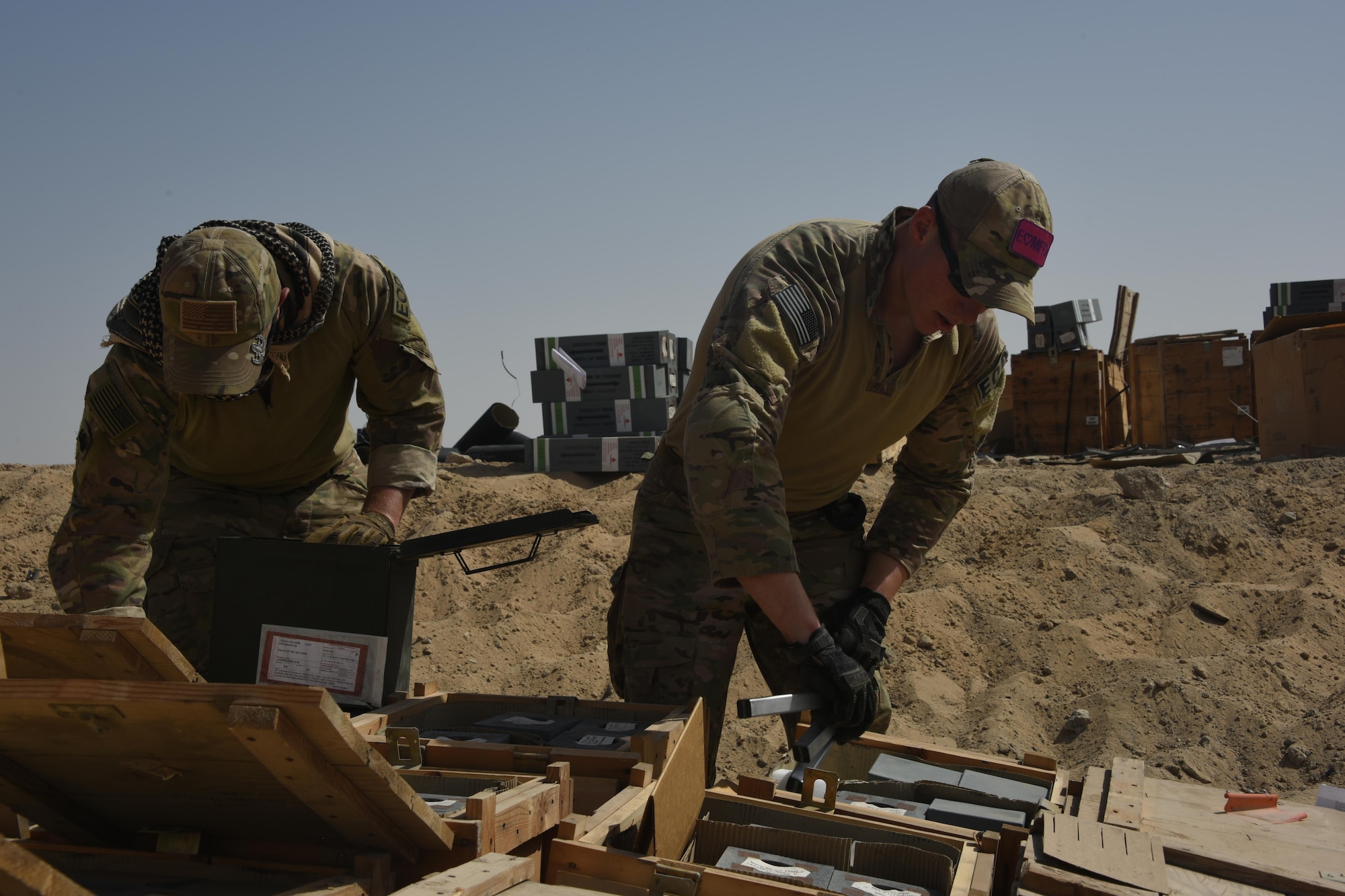 Two Explosive Ordnance Disposal technicians with the 386th Expeditionary Civil Engineer Squadron, place flares inside wooden crates during an ammunition disposal request burn operation at an undisclosed location in Southwest Asia, May 11, 2017. The stockpile of expired munitions consisting primarily of flares was transported to an isolated location where the unserviceable items were stacked in a man-made hole in preparation for destruction. (U.S. Air Force photo/ Tech. Sgt. Jonathan Hehnly)