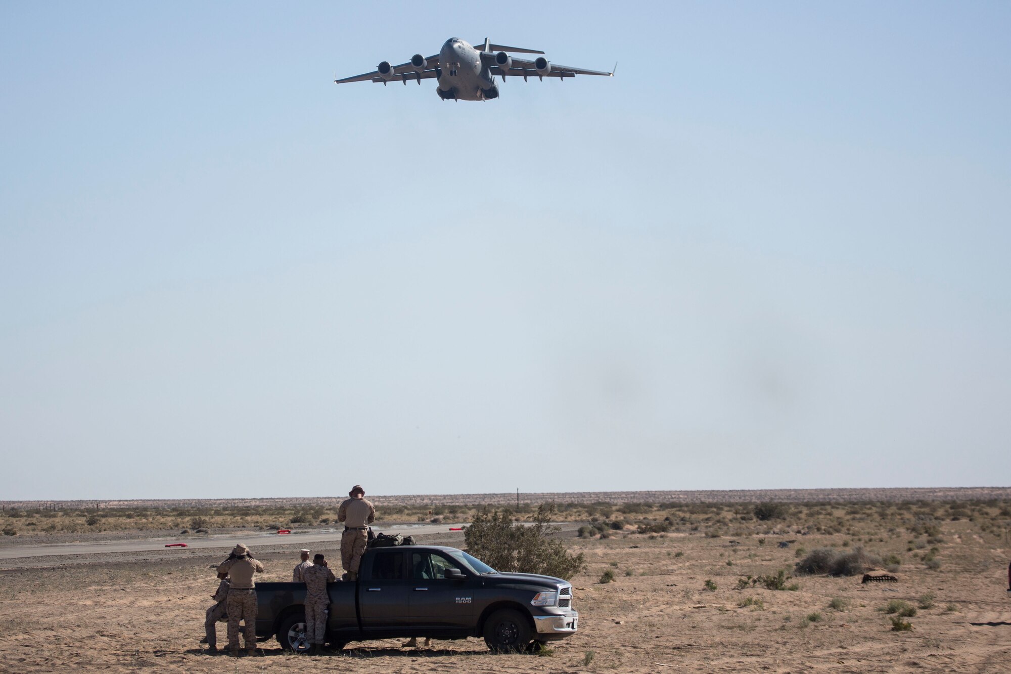 A U.S. Marine Corps Air Traffic Control Mobile Team (MMT) watches an Air Force C-17 Globemaster III from the 3rd Airlift Squadron approach during Weapons and Tactics Instructors Course (WTI) 2-17 at Auxiliary Airfield II, Yuma, Ariz., April 19, 2017. WTI is a seven-week training event hosted by MAWTS-1 cadre, which emphasizes operational integration of the six functions of Marine Corps aviation in support of a Marine Air Ground Task Force and provides standardized advanced tactical training and certification of a unit instructor qualifications to support Marine Aviation Training and Readiness and assist in developing and employing aviation weapons and tactics. (U.S. Marine Corps photo by Lance Cpl. Luis Quinones)