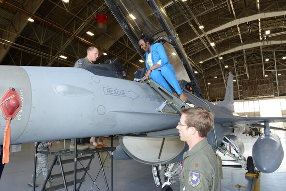Tiffanii Woolfolk climbs up to the cockpit of an F-16 Fighting Falcon in Hangar 1207 as Col. Jason Schott, 412th Test Wing vice commander (left), and Maj. Philip Jackson, 416th Flight Test Squadron, guide her in. Woolfolk was one of three congressional staffers who visited Edwards May 10. (U.S. Air Force photo by Kenji Thuloweit)