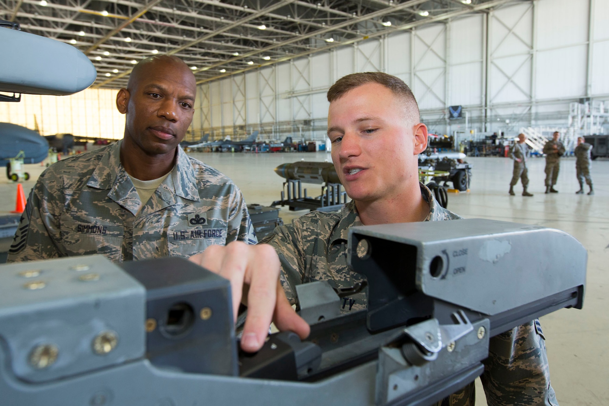 Chief Master Sgt. Todd Simmons, 412th Test Wing command chief (left), is provided guidance by Senior Airman Travis Dougherty, 412th Maintenance Group, on an F-16 Fighting Falcon launcher rail before loading an AIM-9X missile on the aircraft May 11 at Hangar 1600. (U.S. Air Force photo by Christopher Okula)