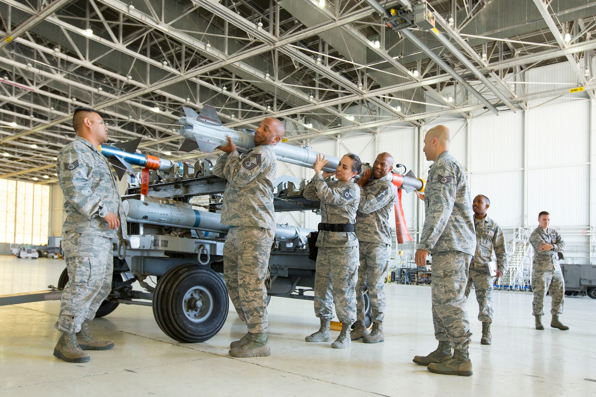Holding the missile, from left to right: Chief Master Sgt. Todd Simmons, 412th Test Wing command chief; Tech. Sgt. Monique Fernandez, 412th TW; and Chief Master Sgt. Roosevelt Jones, 412th Maintenance Group; loaded an AIM-9X Sidewinder short-range air-to-air missile onto an F-16 Fighting Falcon May 11 at Hangar 1600. (U.S. Air Force photo by Christopher Okula)