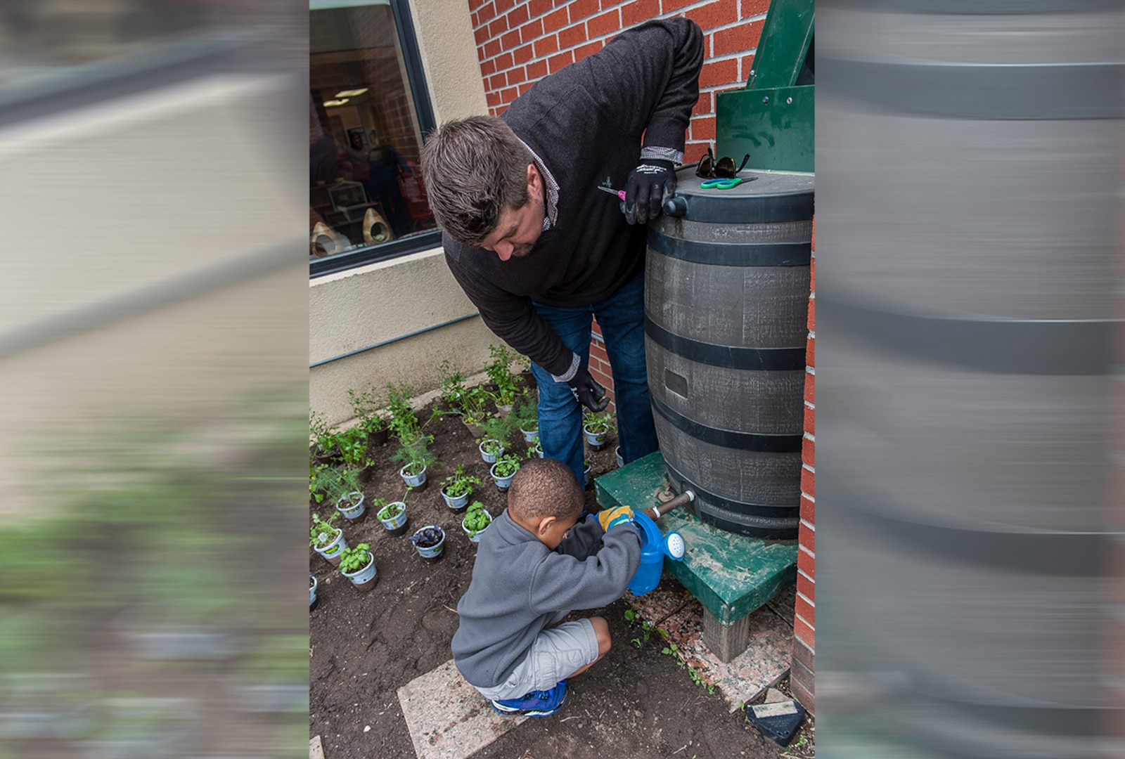Pre-K student retrieves water from the rain barrel at the Child Development Center learning garden.