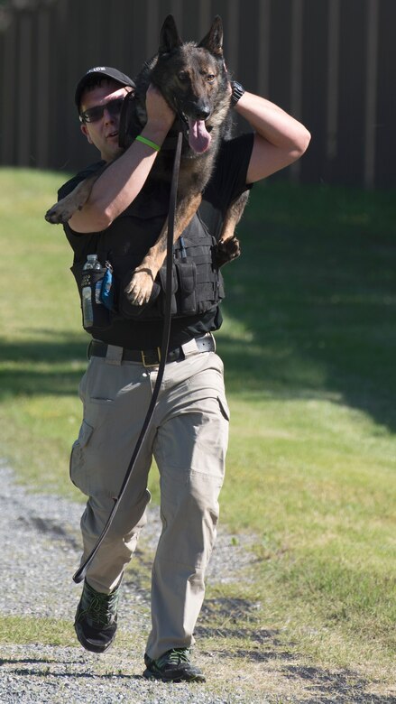 Scott Frazer, Defense Intelligence Agency K-9 handler, carries his dog during the 2017 National Police Week Military Working Dog Iron Dog Competition at Joint Base Andrews, Md., May 16, 2017. The competition took dogs and handlers on a 5K trot through the trails on base. This was one of multiple events meant to honor and thank the law enforcement officers who serve for their dedication and service to local communities. (U.S. Air Force photo by Airman 1st Class Valentina Lopez)