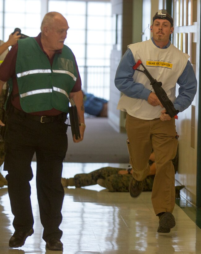 A simulated active shooter runs down a hall way during an Active Shooter Full Scale Exercise at Robert E. Bush Naval Hospital, aboard Marine Corps Air Ground Combat Center Twetynine Palms, Calif., May 16, 2017. The exercise allowed for the naval hospital, Provost Marshals Office, Fire Department and Naval Criminal Investigative Service to practice and assess their ability to detect, identify and respond to an active shooter incident, validating emergency response procedures. (U.S.Marine Corps photo by Cpl. Thomas Mudd)