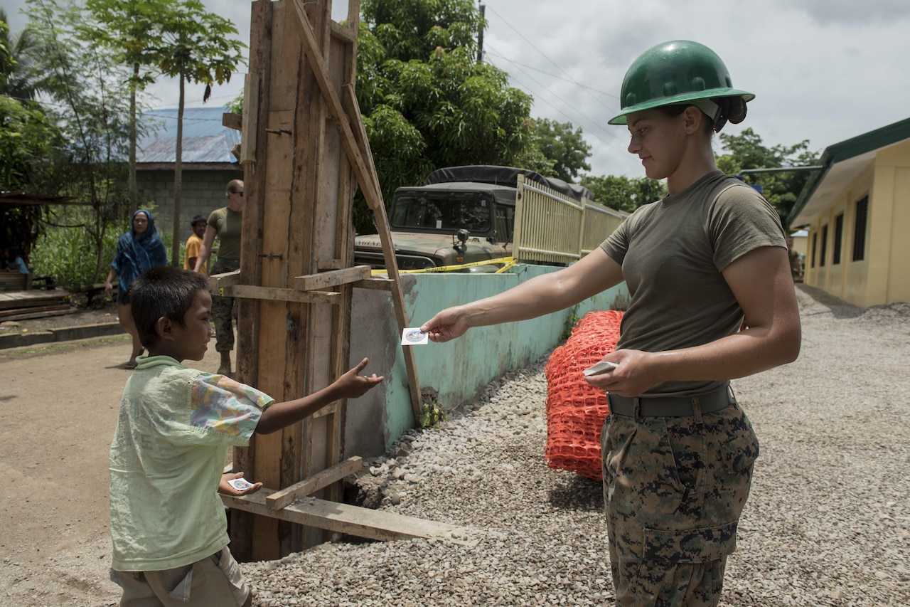 U.S. Marine Lance Cpl. Brook Klahn, right, gives a Balikatan sticker to a boy at an engineering civic assistance project site in support of Balikatan 2017 in Ormoc City, Leyte, May 14, 2017. Philippine and U.S. service members worked together to build new classrooms for students at Don Carlos Elementary School. Balikatan is an annual U.S.-Philippine bilateral military exercise focused on a variety of missions, including humanitarian assistance and disaster relief, counterterrorism, and other combined military operations. 