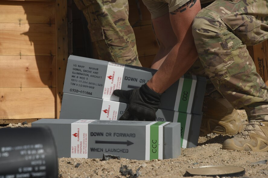 An explosive ordnance disposal technician, with the 386th Expeditionary Civil Engineer Squadron, prepares to lift a stack of flares during an ammunition disposal request burn operation at an undisclosed location in Southwest Asia May 11, 2017. A group of EOD technicians, ammunition personnel and firefighters from the 386th Air Expeditionary Wing worked together to dispose of a truckload of expired ordnances in a safe manner at an isolated location. (U.S. Air Force photo/Tech. Sgt. Jonathan Hehnly)