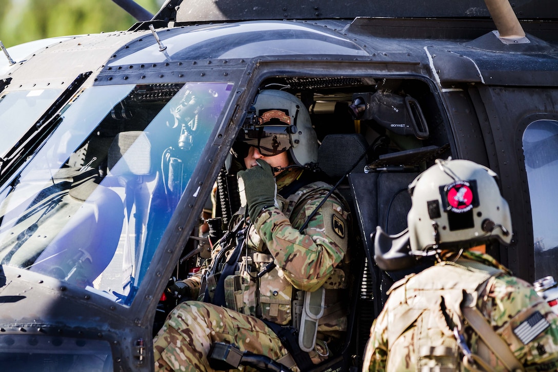 An Army pilot inside a UH-60 Black Hawk helicopter communicates with a crew chief to prepare for a mission at Operating Base Fenty, Jalalabad, Afghanistan, May 17, 2017. Army photo by Capt. Brian Harris