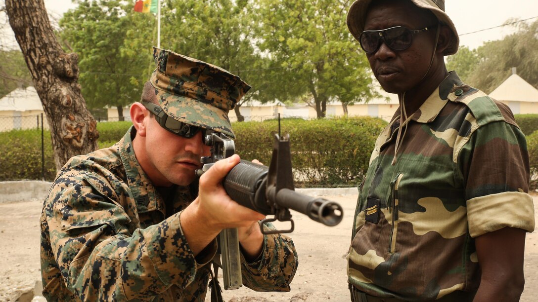 Sgt. Timothy Kuklis, an assaultman with Special Purpose Marine Air-Ground Task Force – Crisis Response – Africa, demonstrates the standing firing position to a member of Senegal’s Compagnie Fusilier de Marin Commando during a four-week training exercise at Toubakouta, Senegal, April 12, 2017. Marines with SPMAGTF-CR-AF and the COFUMACO conducted a four-week training exercise that included advanced combat firing techniques, a machine gun range and a live-fire platoon attack range. 