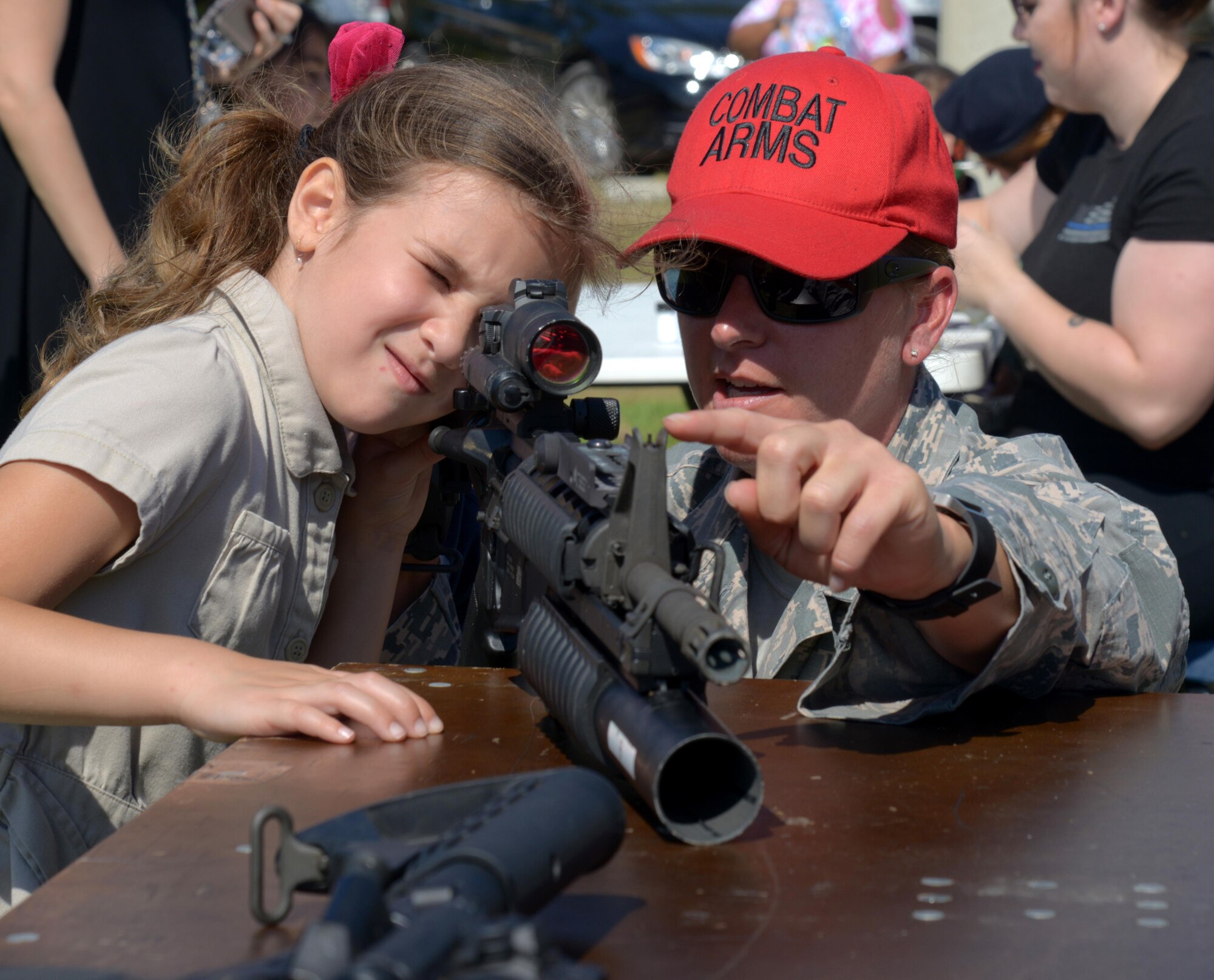 U.S. Air Force Tech. Sgt. Nicole Ogilvie, NCO in charge of combat arms training and maintenance assigned to the 6th Security Forces Squadron (SFS), teaches a Tinker Elementary School student to look through an M68 sight on an M4 carbine at MacDill Air Force Base, Fla., May 16, 2017. The 6th SFS celebrated National Police Week with multiple events to include setting up police displays for the students. (U.S. Air Force photo by Senior Airman Tori Long)
