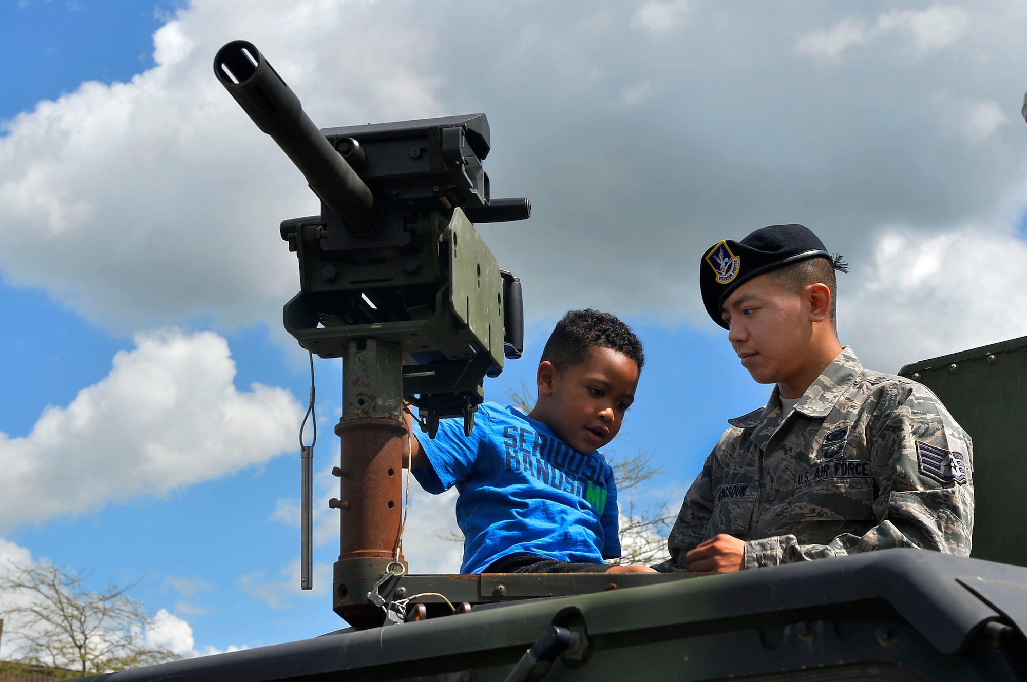 Staff Sgt. Jesse Sengsouk, 435th Security Forces Squadron training instructor, shows a child the functions of a gun on a Humvee during a police display on Ramstein Air Base, Germany, May 13, 2017. The family event exhibited a variety of vehicles, weapons, information booths, and demonstrations. (U.S. Air Force photo by Airman 1st Class Joshua Magbanua) 
