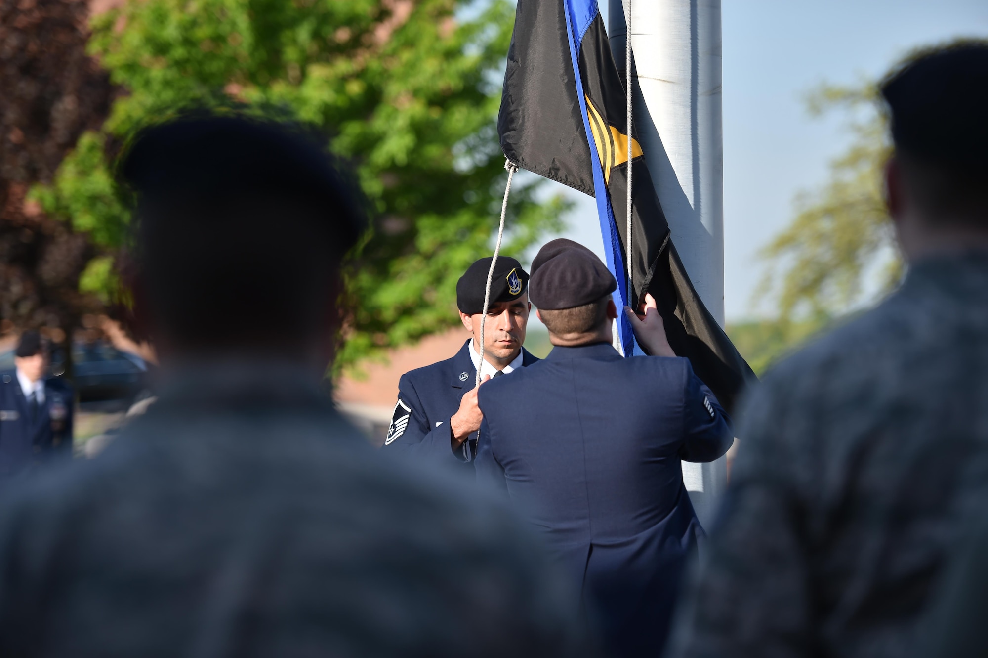 Master Sgt. Loren Mount, flight sergeant, and Tech. Sgt. Wesley Whitaker, fire team leader, both with the 910th Security Forces Squadron (SFS), raise a police memorial flag to half-mast outside the headquarters building here, while SFS members stand in formation at attention May 17, 2017. SFS held a ceremony with representatives from local law enforcement agencies in recognition of Police Week. The ceremony honored the selfless service of U.S. police officers who have fallen in the line of duty. (U.S. Air Force photo/Eric White)