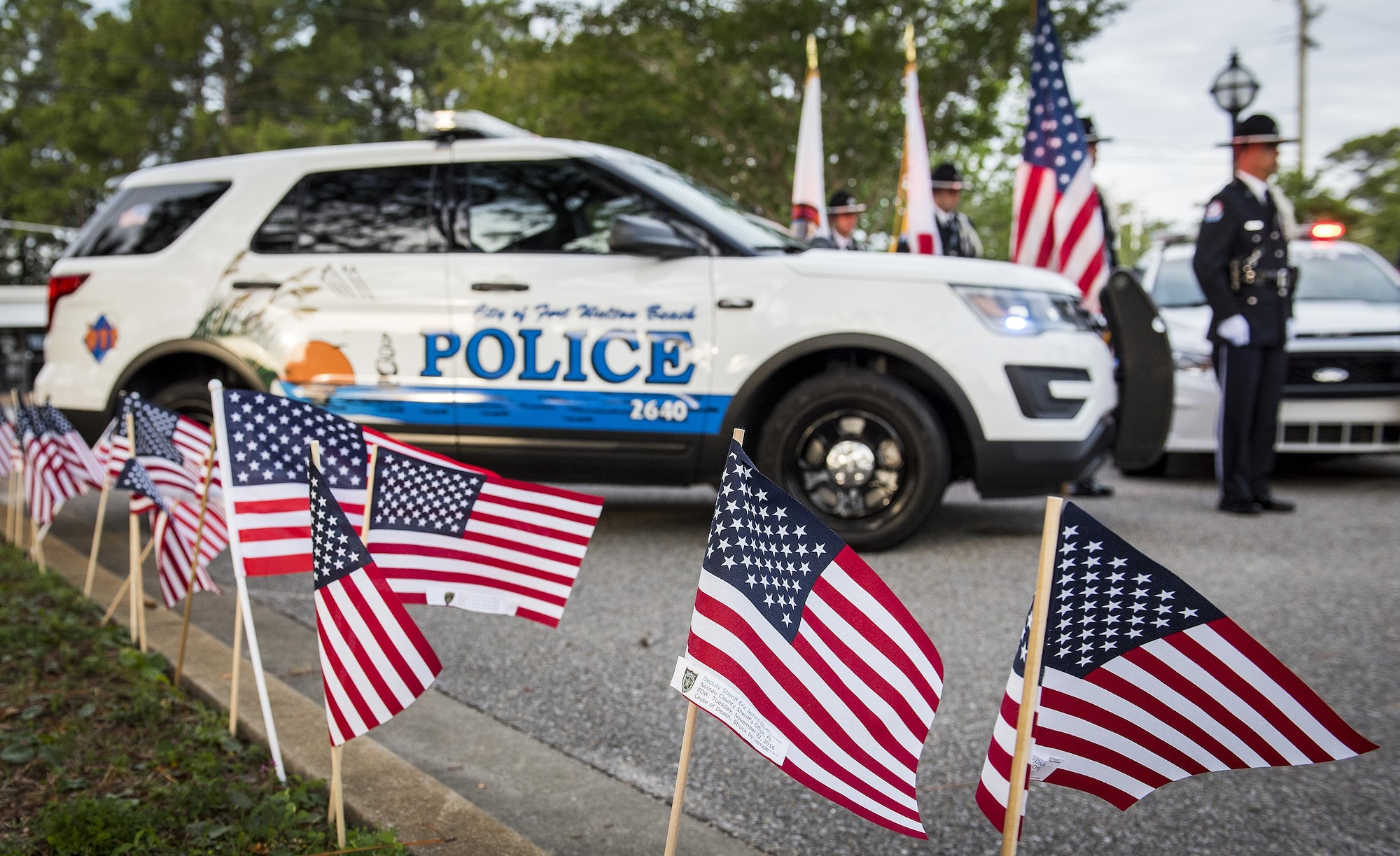 American Flags flap in the breeze as Fort Walton Beach Police Department color guard members wait to bring in the colors during the Peace Officers’ Memorial Ceremony May 18 in Fort Walton Beach, Fla. The ceremony was to honor fallen police officers from the previous year by reading their names aloud. Security forces Airmen from Eglin and Hurlburt Field attended and participated in the event. The ceremony is one of many events taking place during National Police Week. (U.S. Air Force photo/Samuel King Jr.)