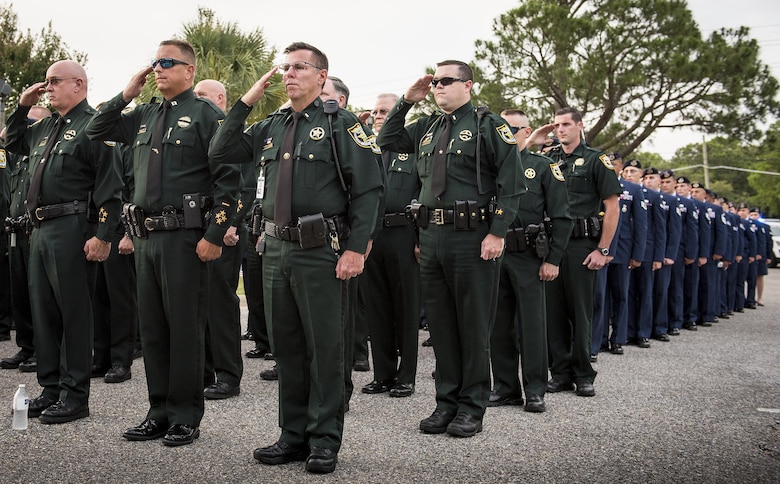 Okaloosa County Sheriff’s Officers and Air Force Security Forces Airmen salute during the posting of the colors at the Peace Officers’ Memorial Ceremony May 18 in Fort Walton Beach, Fla. The ceremony was to honor fallen police officers from the previous year by reading their names aloud. Security forces Airmen from Eglin and Hurlburt Field attended and participated in the event. The ceremony is one of many events taking place during National Police Week. (U.S. Air Force photo/Samuel King Jr.)
