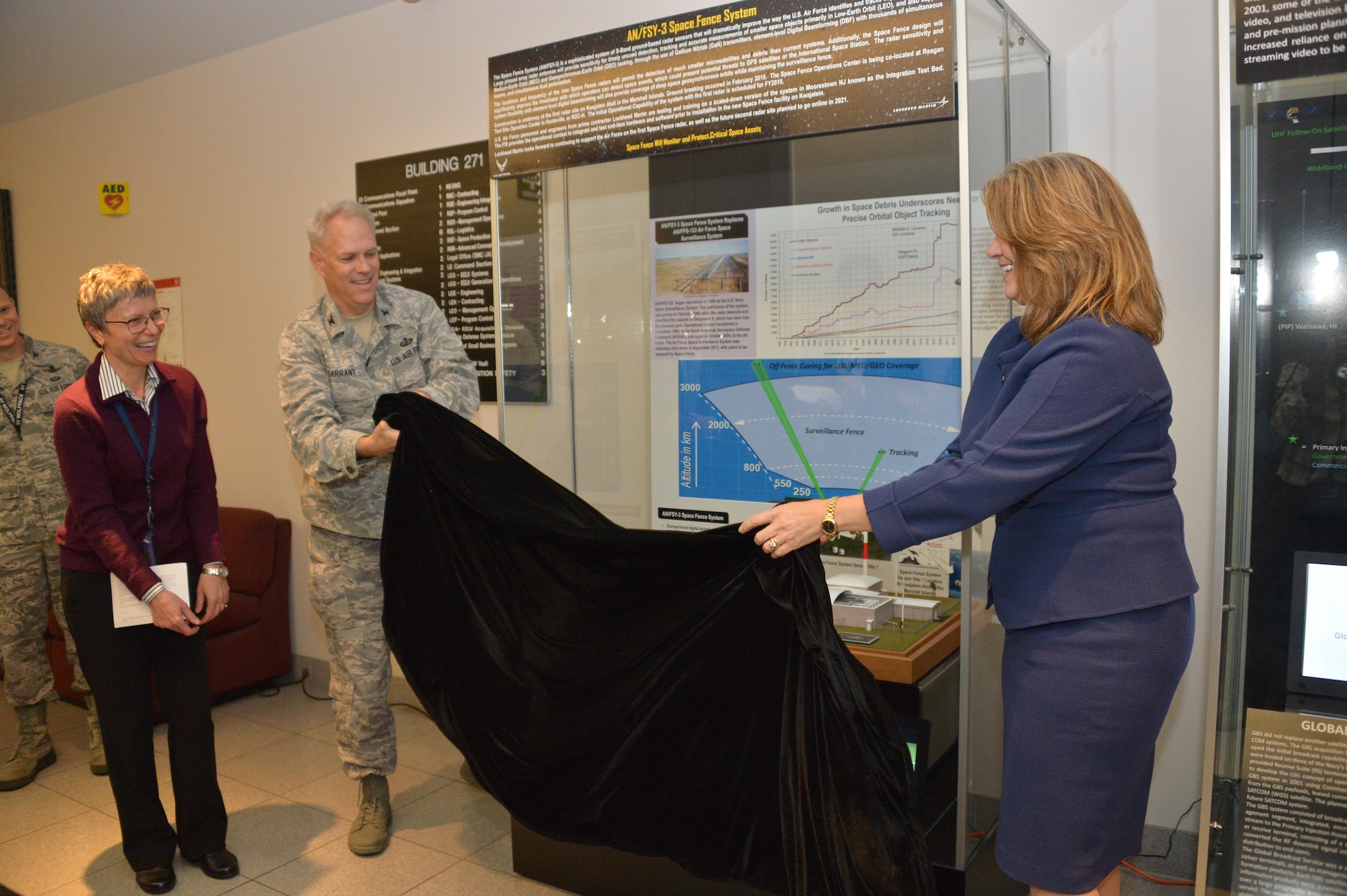 Michele Evans, vice president and general manager of Integrated Warfare Systems and Sensors for Lockheed Martin Rotary and Mission Systems, accompanied by Robert Condren, Don Tomajen and Nancy FitzGerald, assist Col. Phil Garrant, director of the Space and Missile Systems Center's Space Superiority Directorate in unveiling a new information display at the SMC Heritage Center at Los Angeles Air Force Base in El Segundo, California, May 11, 2017.