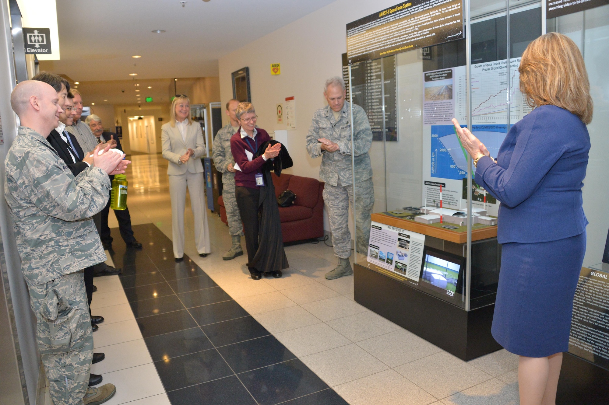Michele Evans, vice president and general manager of Integrated Warfare Systems and Sensors for Lockheed Martin Rotary and Mission Systems, accompanied by Robert Condren, Don Tomajen and Nancy FitzGerald, assist Col. Phil Garrant, director of the Space and Missile Systems Center's Space Superiority Directorate in unveiling a new information display at the SMC Heritage Center at Los Angeles Air Force Base in El Segundo, California, May 11, 2017.