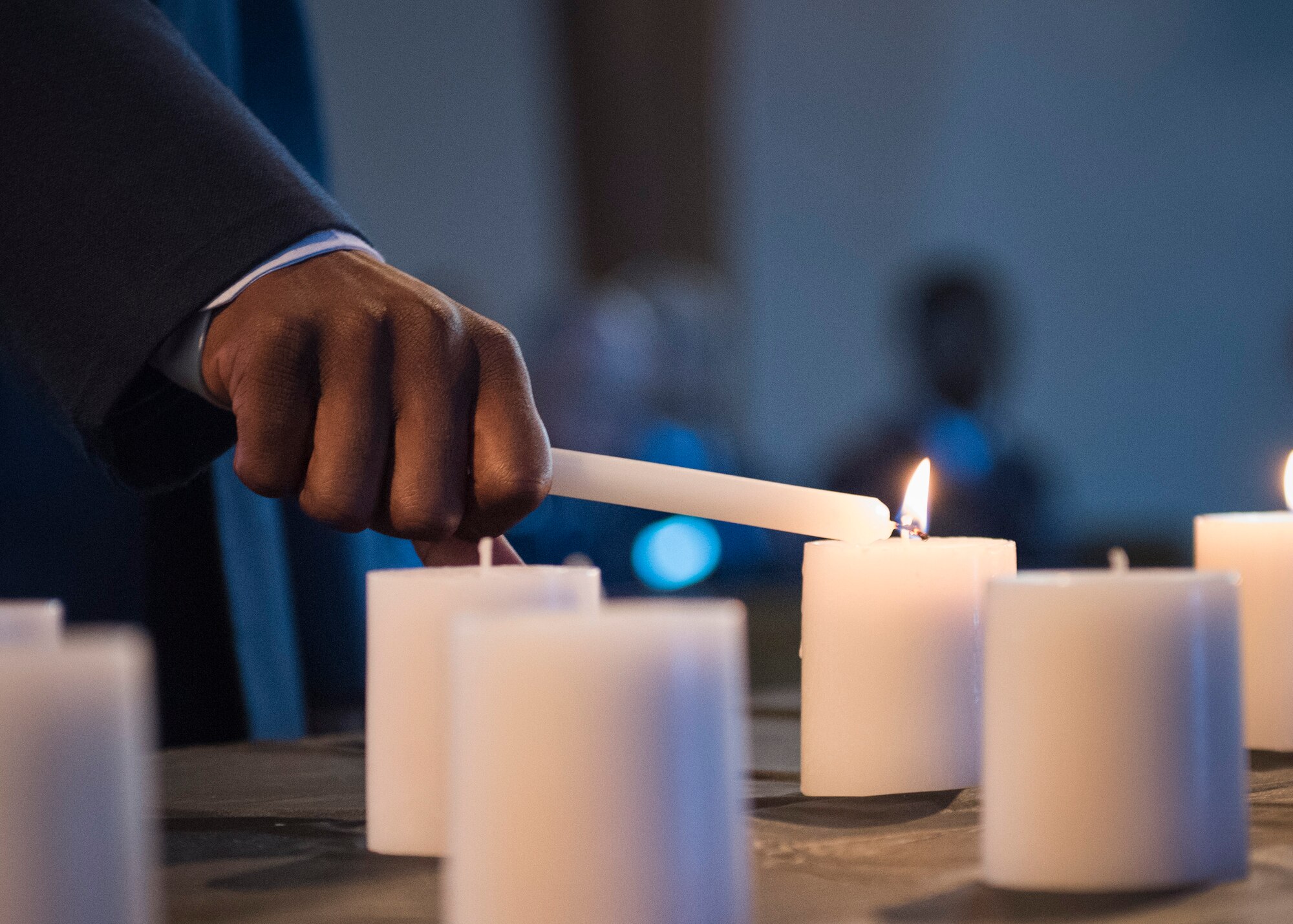 A 96th Security Forces Squadron Airman lights a candle during the National Police Week candlelight vigil May 18 at Eglin Air Force Base, Fla. The ceremony was held to honor the police, defenders and the agents who paid the ultimate sacrifice in the line of duty. To remember them 14 candles were lit. (U.S. Air Force photo/Ilka Cole)